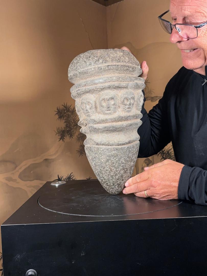De la zona del río Columbia, en el noroeste de la América Nativa, procede este cuenco o mortero ceremonial de piedra basáltica, tallado a mano, antiguo, sustancial y único, con nueve (9) cabezas humanas dentro de una doble banda circular, río