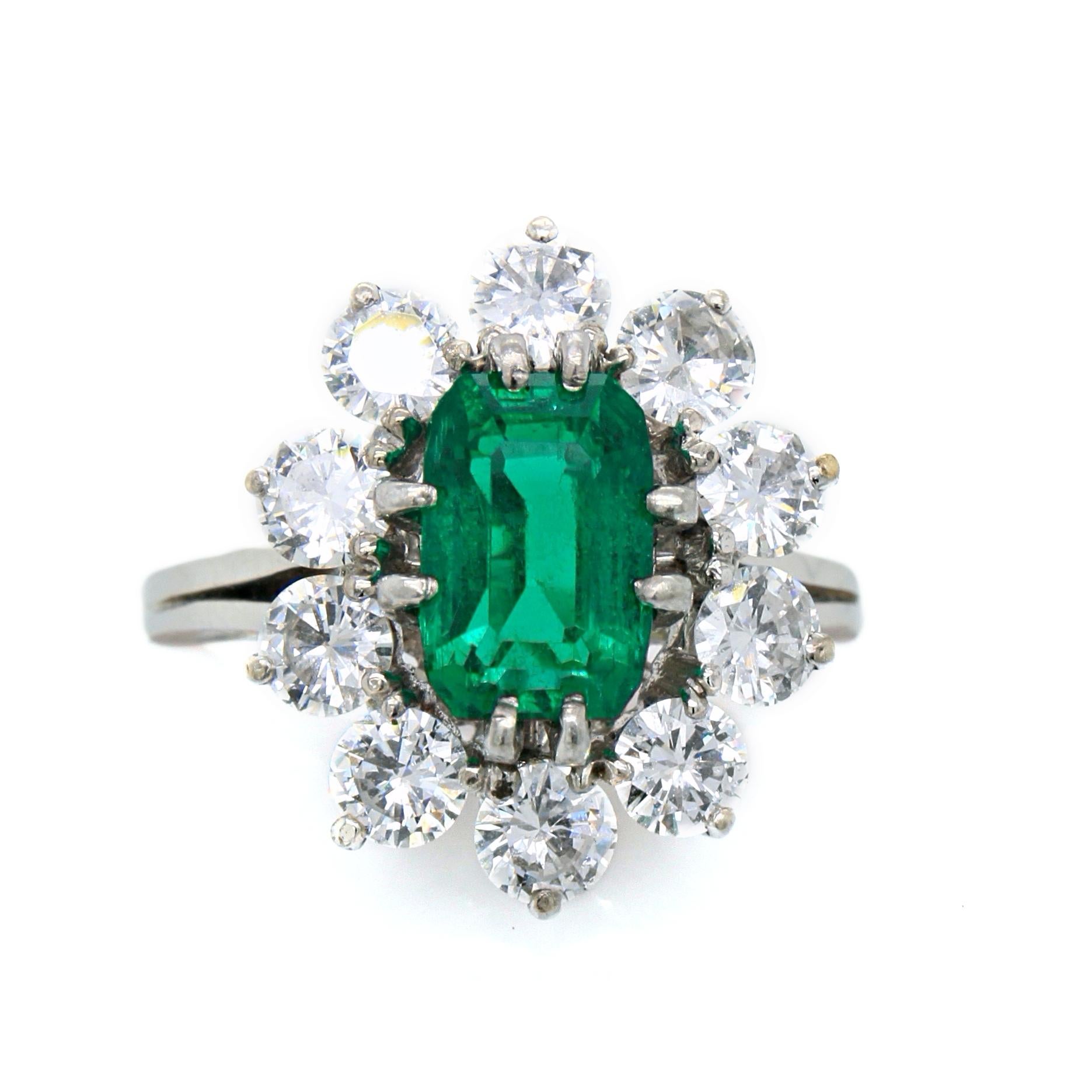 A French emerald and diamond ring in platinum and 18k. 

The centre emerald weighs 1.88 carats and is of Columbian origin and Minor Oil, accompanied by a gemological certificate. It has as a vivid deep green colour, very clear crystal and no eye