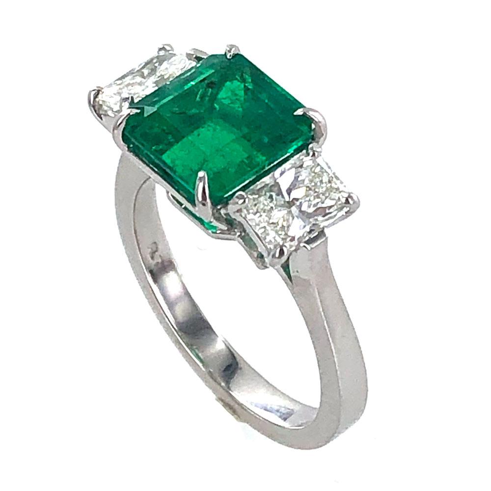 Magnificent deep green emerald and diamond ring crafted in platinum. The 3.11 carat step cut Colombian emerald has been certified by the GIA F1 minor. The emerald is flanked by two radiant cut diamonds weighing approximately 1.10 carat total weight.