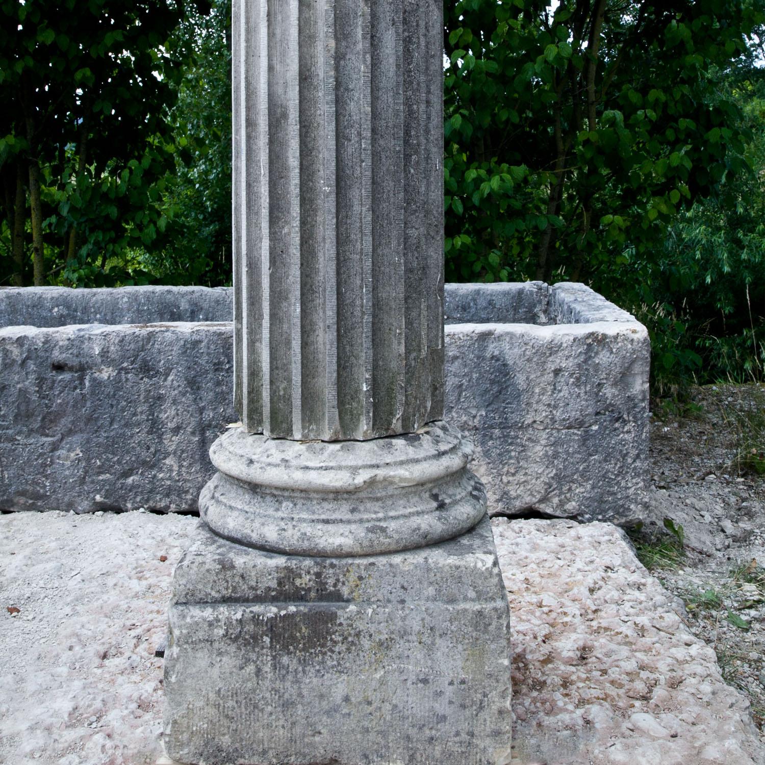 Tall column on a square plinth with a round base, a fluted shaft and a round capital. Naturally aged patina.