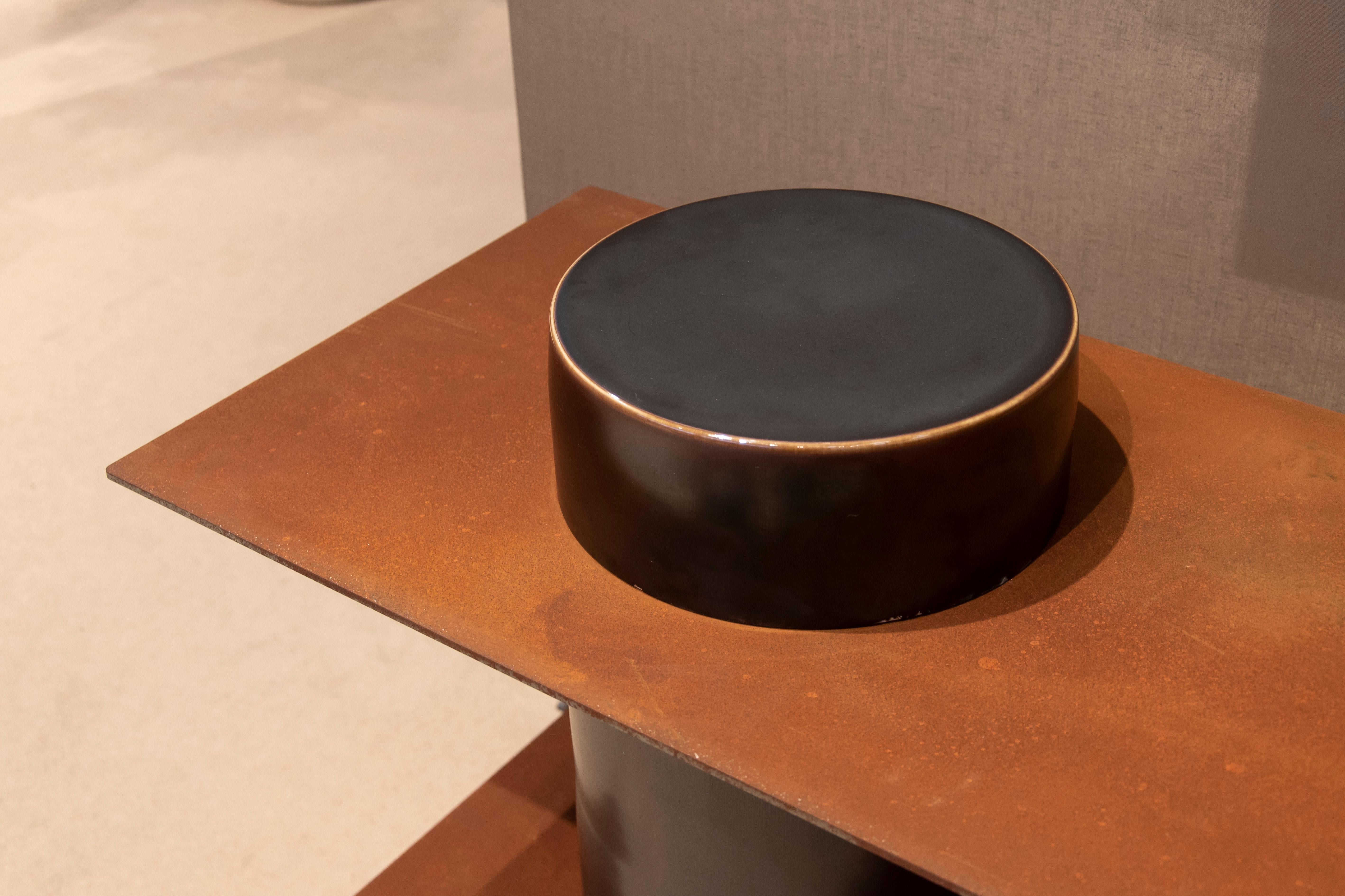 Porcelain cylinders and corten steel plates form the basic elements of this series, with which it is possible to create shelving, side tables, low tables and stools. The porcelain parts are hand thrown, trimmed, glazed and fired at 1300 C by the