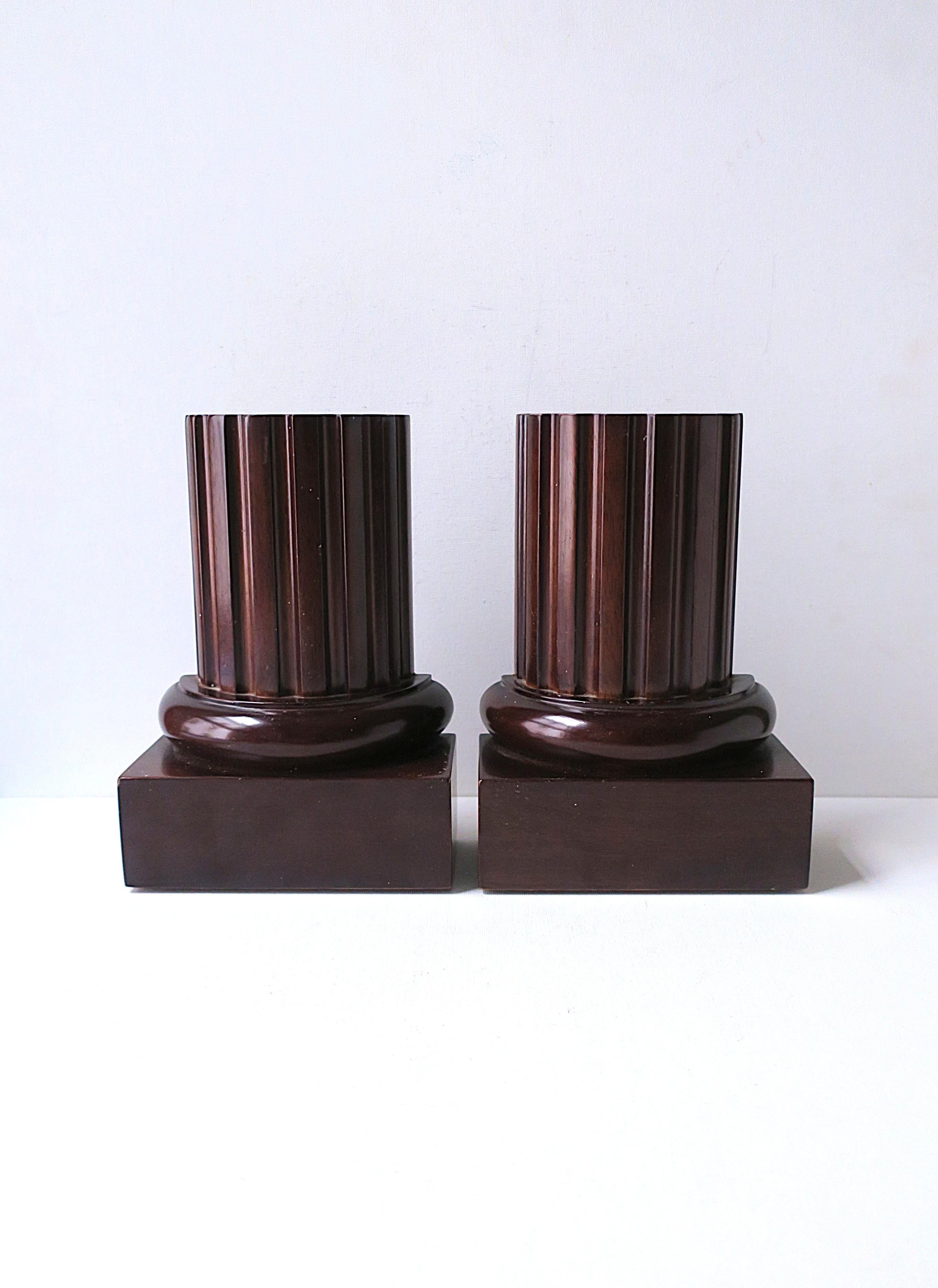 A rich pair of brown wood fluted column bookends, in the Neoclassical design style, circa late-20th century. 