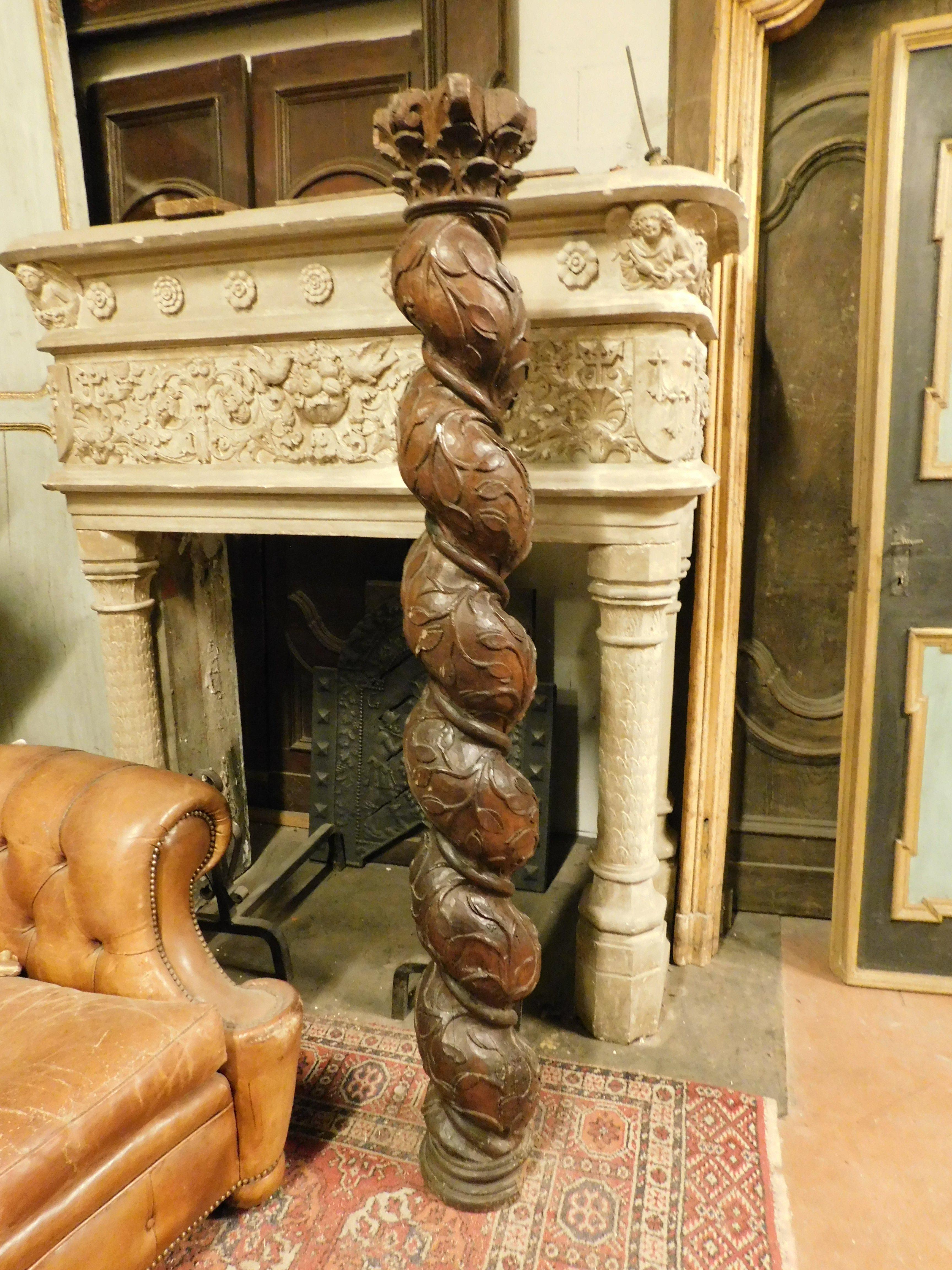 Ancient column in dark brown walnut wood, hand-sculpted with a twisted shape, richly decorated with floral motifs and original capital, from a 17th century. Origin: Italy, note in the photo a small defect due to the age, on the base of the
