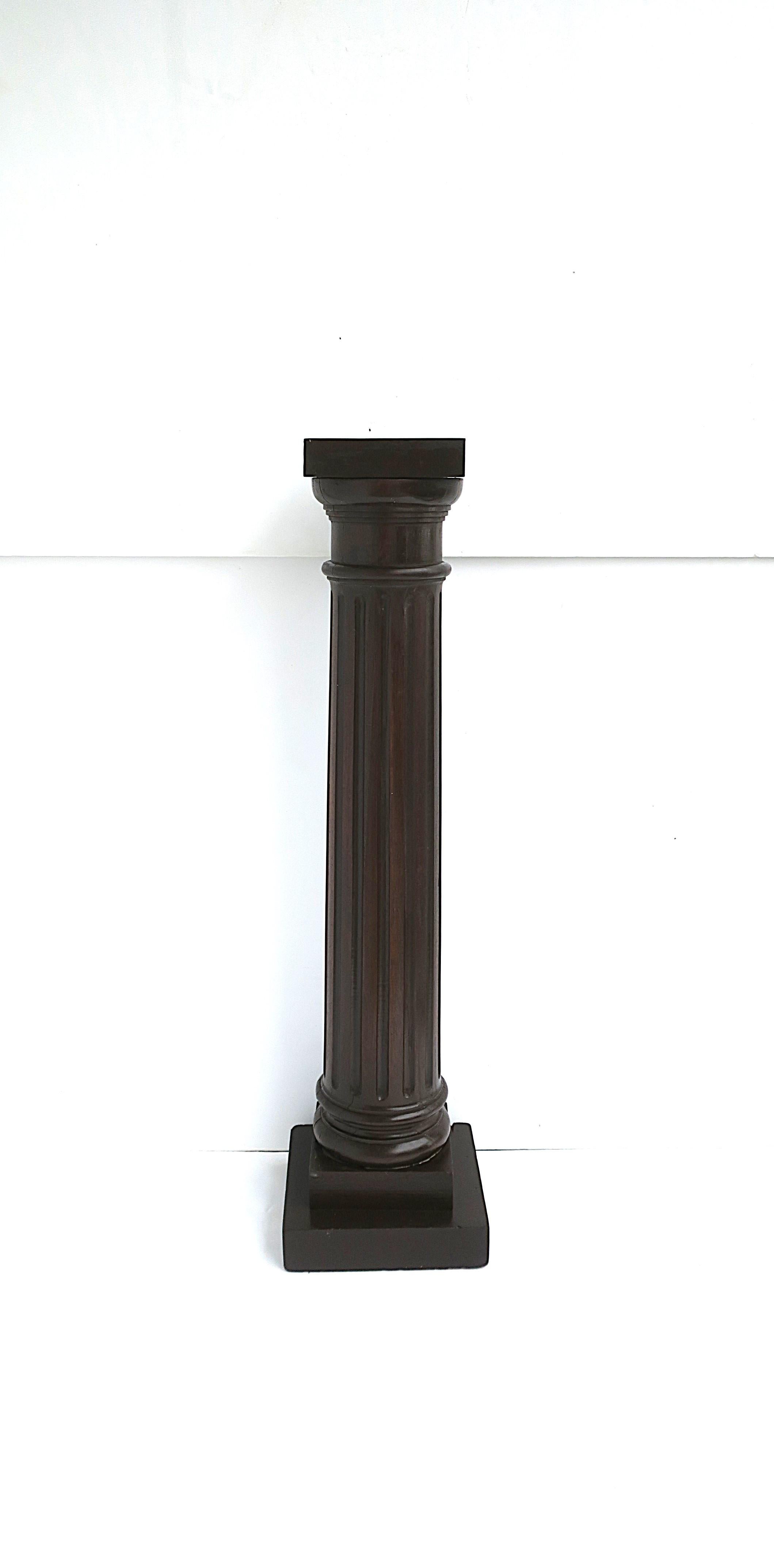 Colonne à piédestal en bois cannelé de style néoclassique, vers le début du XXe siècle. Le piédestal, dont le design se rapproche le plus de la colonne ionique, est en bois brun riche, avec un chapiteau à sommet carré (peint en brun foncé), une tige