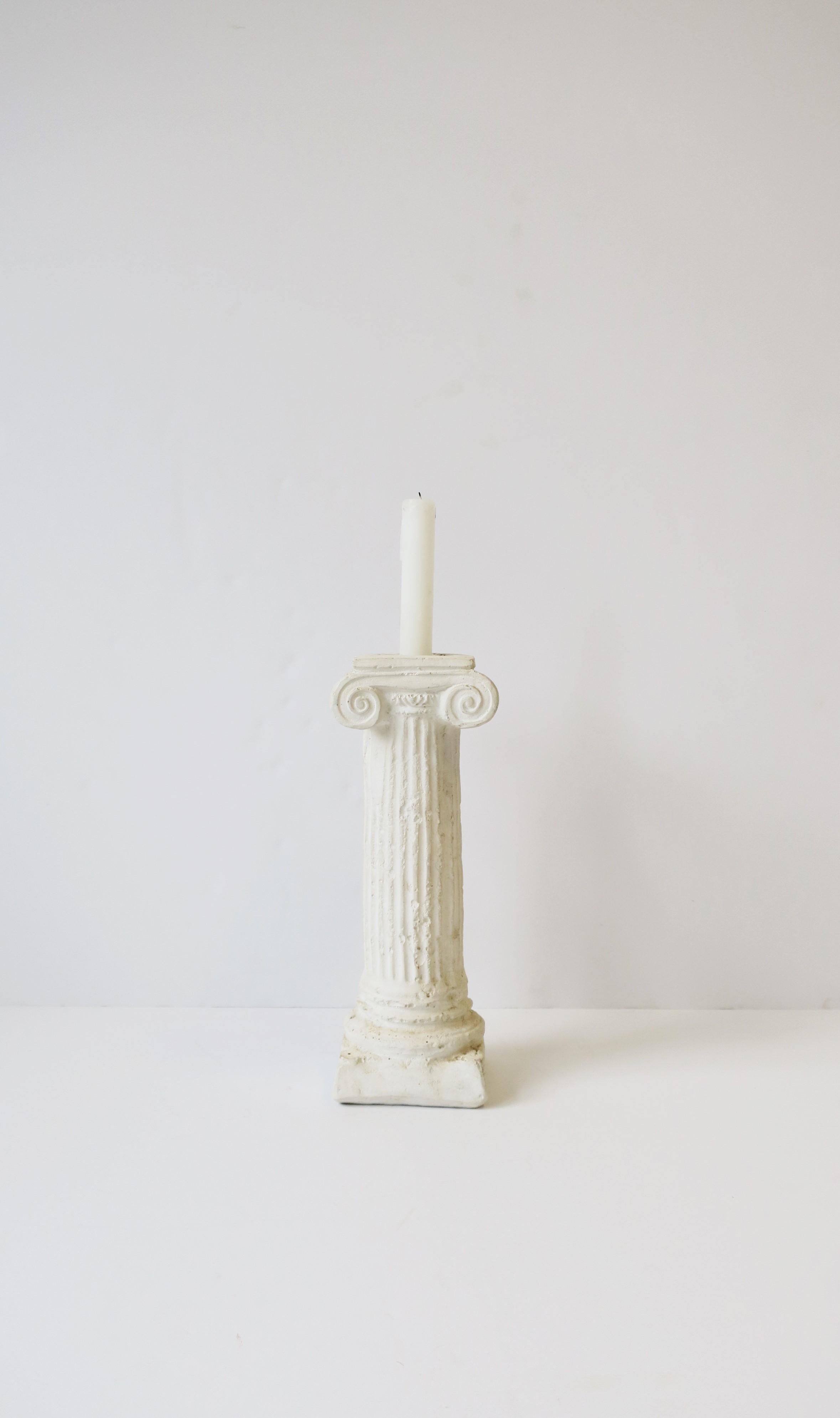 A substantial white plaster Ionic column pillar candlestick holder in the Neoclassical design style, circa 1980s. Candlestick column can also work as a standalone decorative object or bookend. Piece is a nice height measuring 11.07