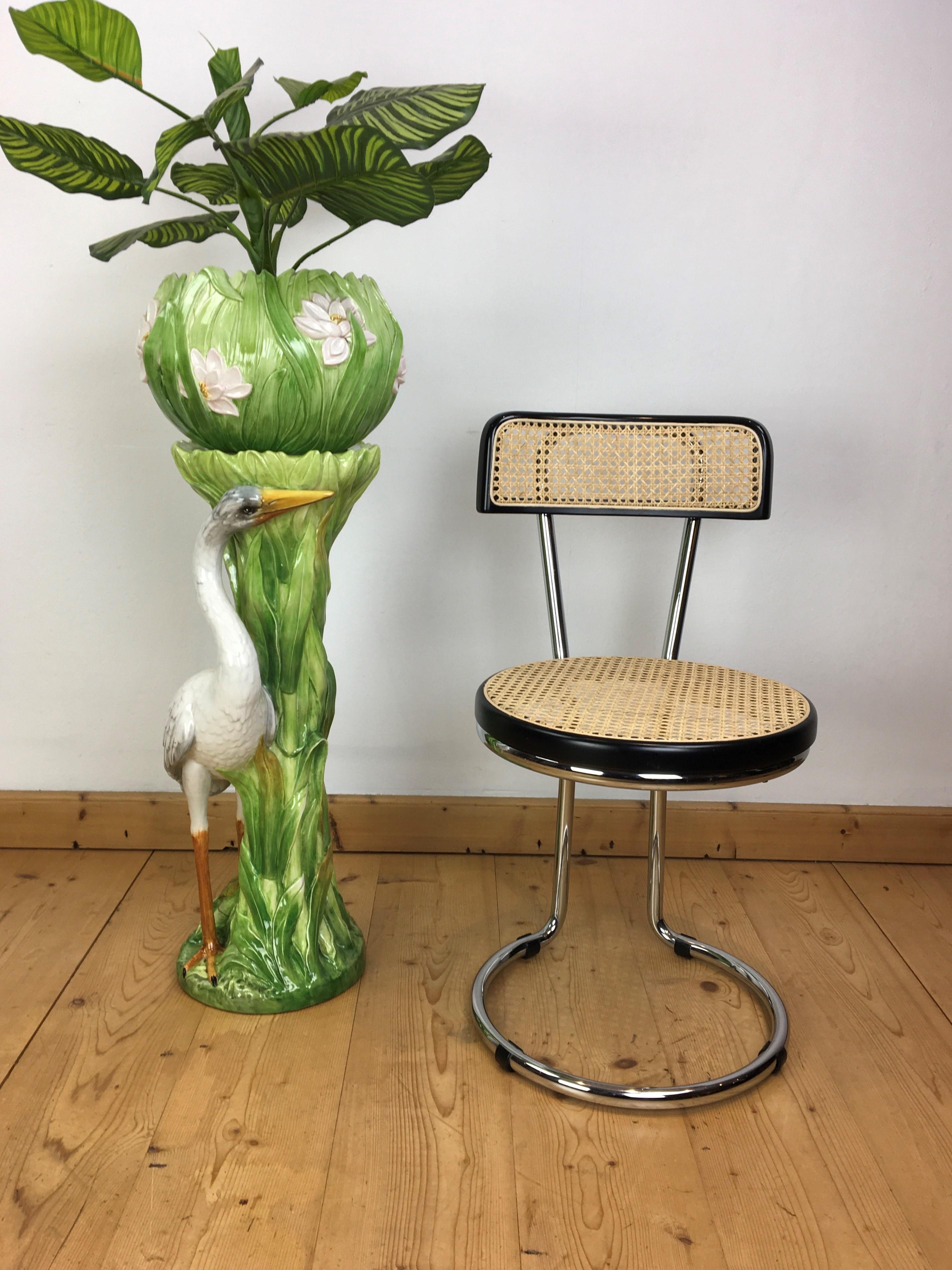 Great looking column with a heron bird and planter on top. 
The column or stand has lots of leaves and a heron bird around. 
The vase or jardinière has beautiful flowers. 
This ceramic planter and stand has beautiful green colors with the flowers