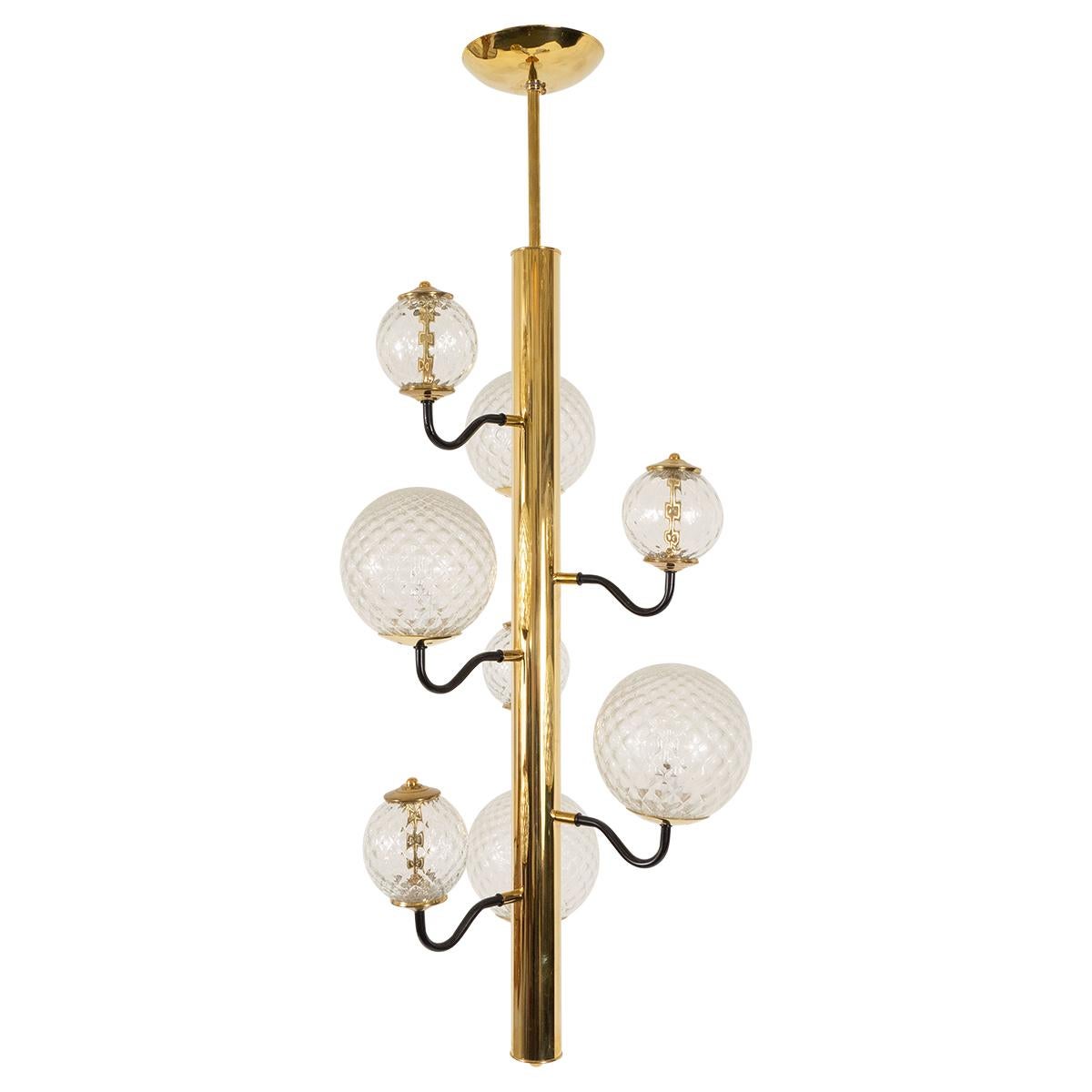 Columnar brass chandelier featuring textured glass globes on black curvilinear arms.