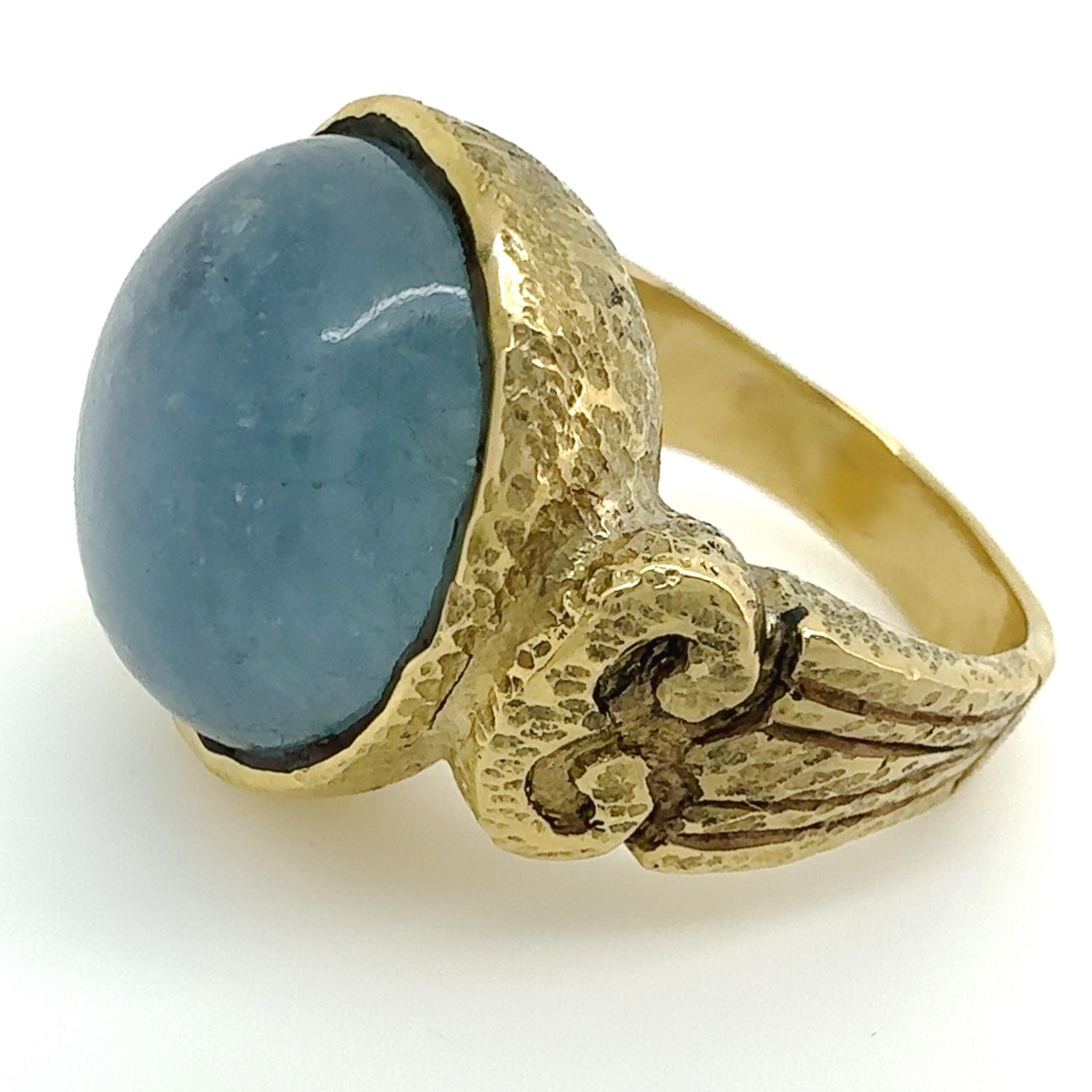 A natural aquamarine cabochon -- round-ish, but not a perfect circle -- is set in an original ring design by Eytan Brandes, featuring classical 