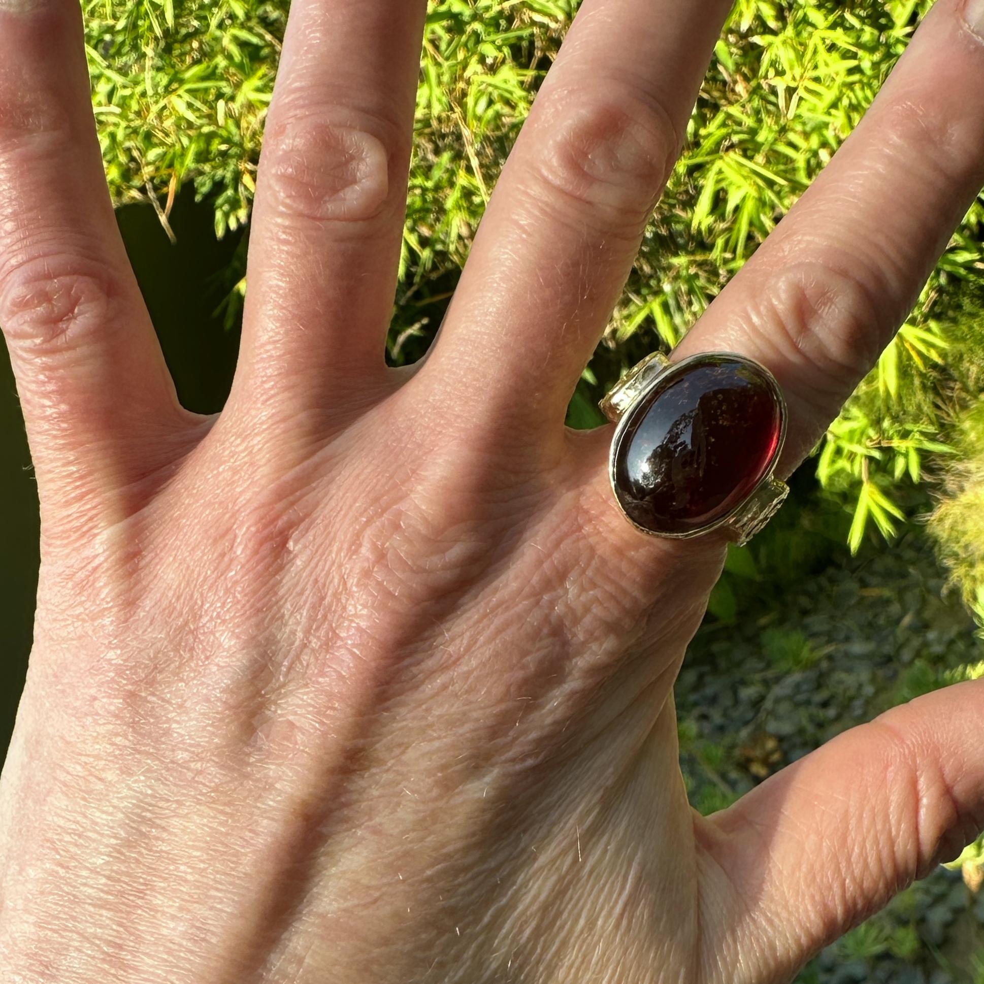 A big, natural dark oxblood red garnet cabochon is set in an original ring design by Eytan Brandes, featuring classical 