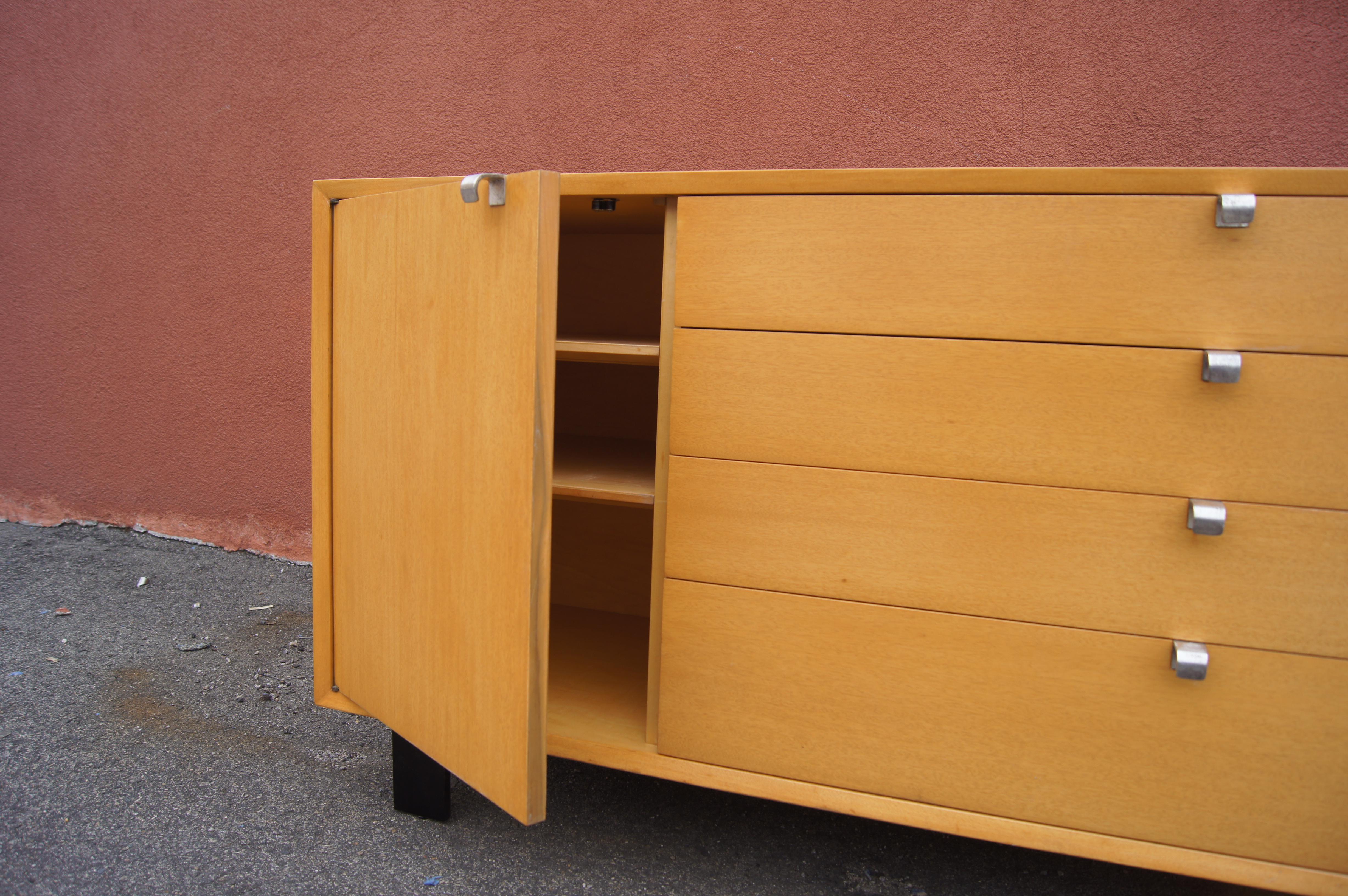 George Nelson designed this comb-grain oak cabinet for Herman Miller as part of their Basic Cabinet Series, sometimes referred to as the Primavera line. The case sits on ebonized block feet. To the left are two adjustable shelves behind a door; on