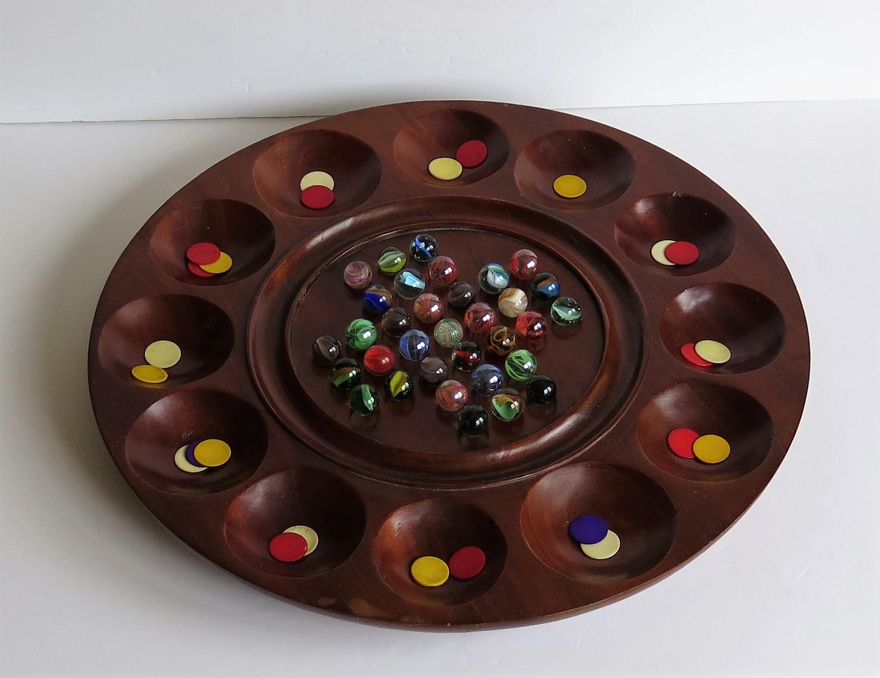 This is a complete combination board game of marble solitaire and tiddlywinks, dating to the early 20th century.

This is a most unusual and very decorative game set with a beautiful board. 

The circular turned board is very attractive being