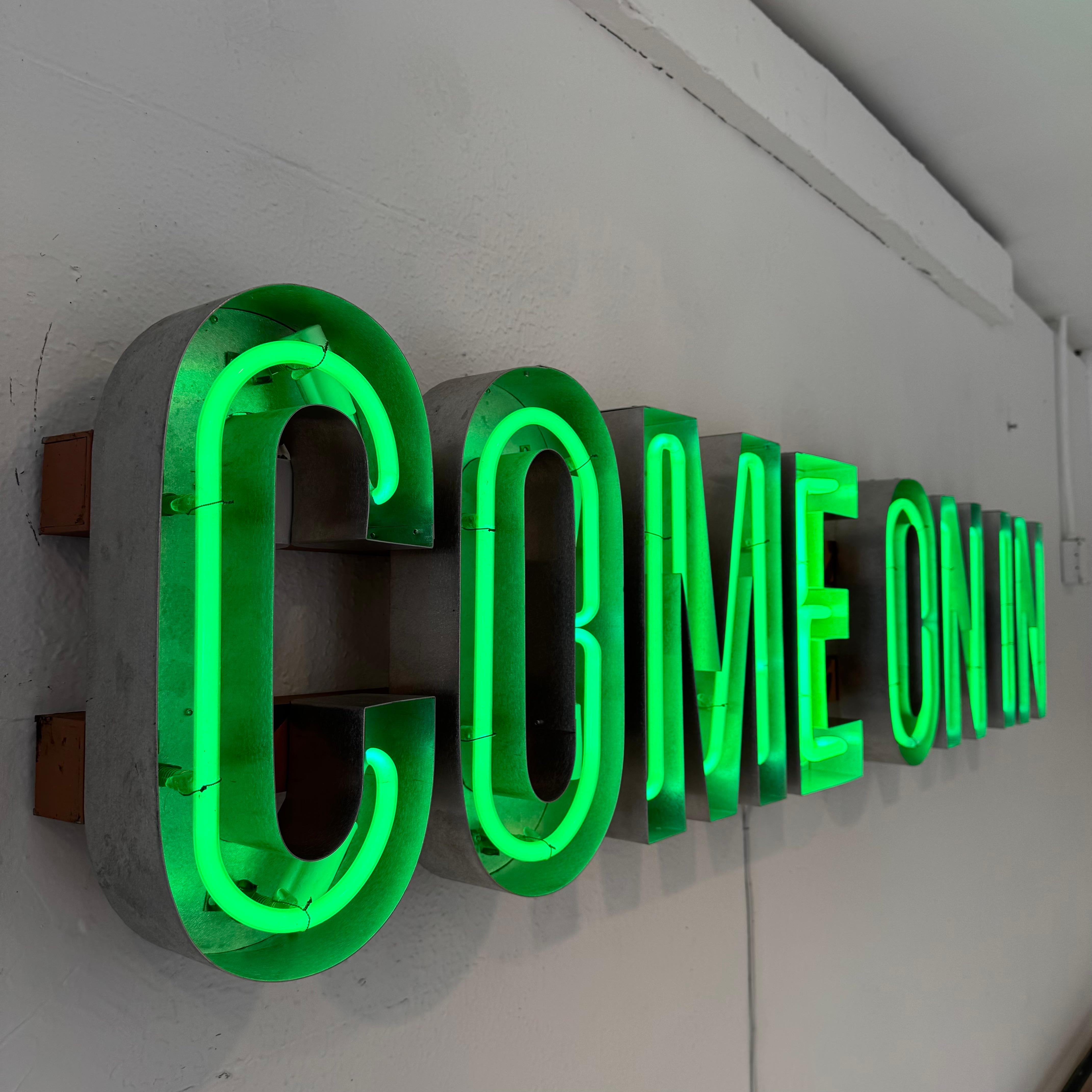 Custom neon sign with aluminum channel cut letters. COME ON IN, lights up with green neon gas. Just under 6 feet long. Welcoming sign and fun piece of art.  Glass in great condition. All letters mounted to two horizontal bars, hiding all of the