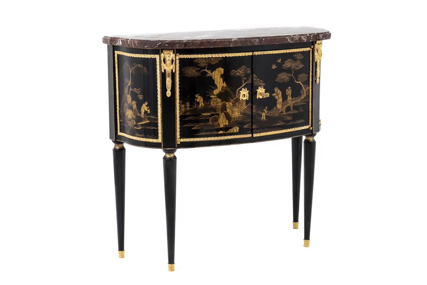 Walter Comelli, stamped.

Half-moon Louis XVI style commode in black lacquer, standing on four tapered legs and opening by two door leaves in front, discovering a red lacquered compartment. Black lacquer adorned with gold Chinese style motifs on
