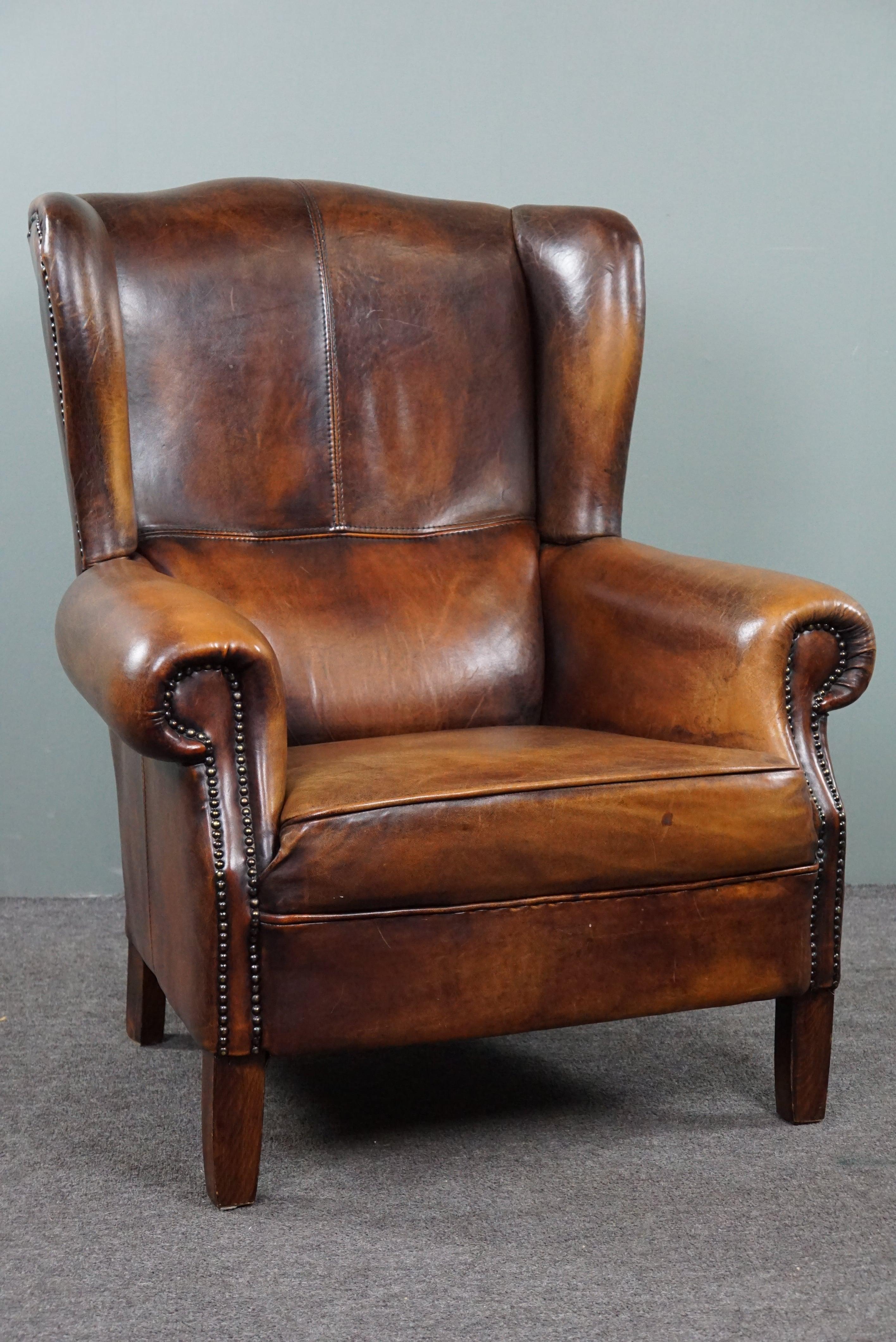 Offered is this striking warm-colored sheepskin leather wing chair.

This striking sheepskin leather wing chair, which is in very good condition, really offers you every comfort and provides your home with a beautiful dose of elegance and character.