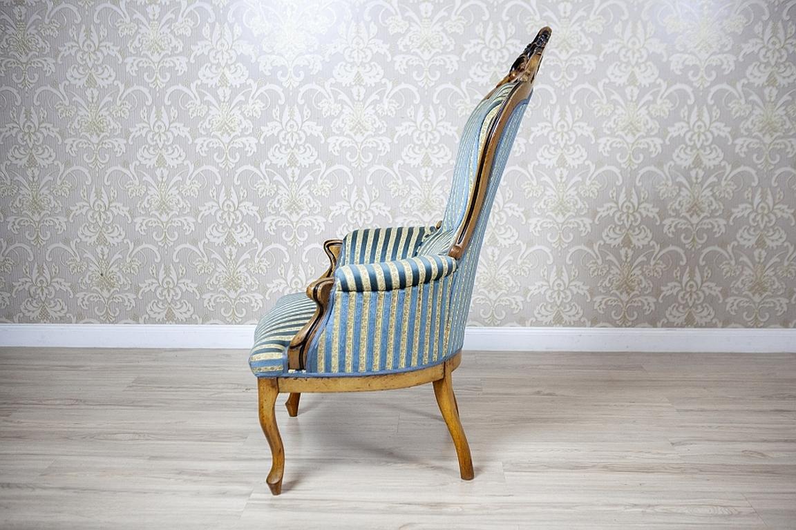 Comfortable Walnut Armchair from the Late 19th Century in Light Blue Upholstery

We present you a walnut armchair from the late 19th century.
The upper section is finished with a crest with a floral motif. Both the backrest, the armrests, and the