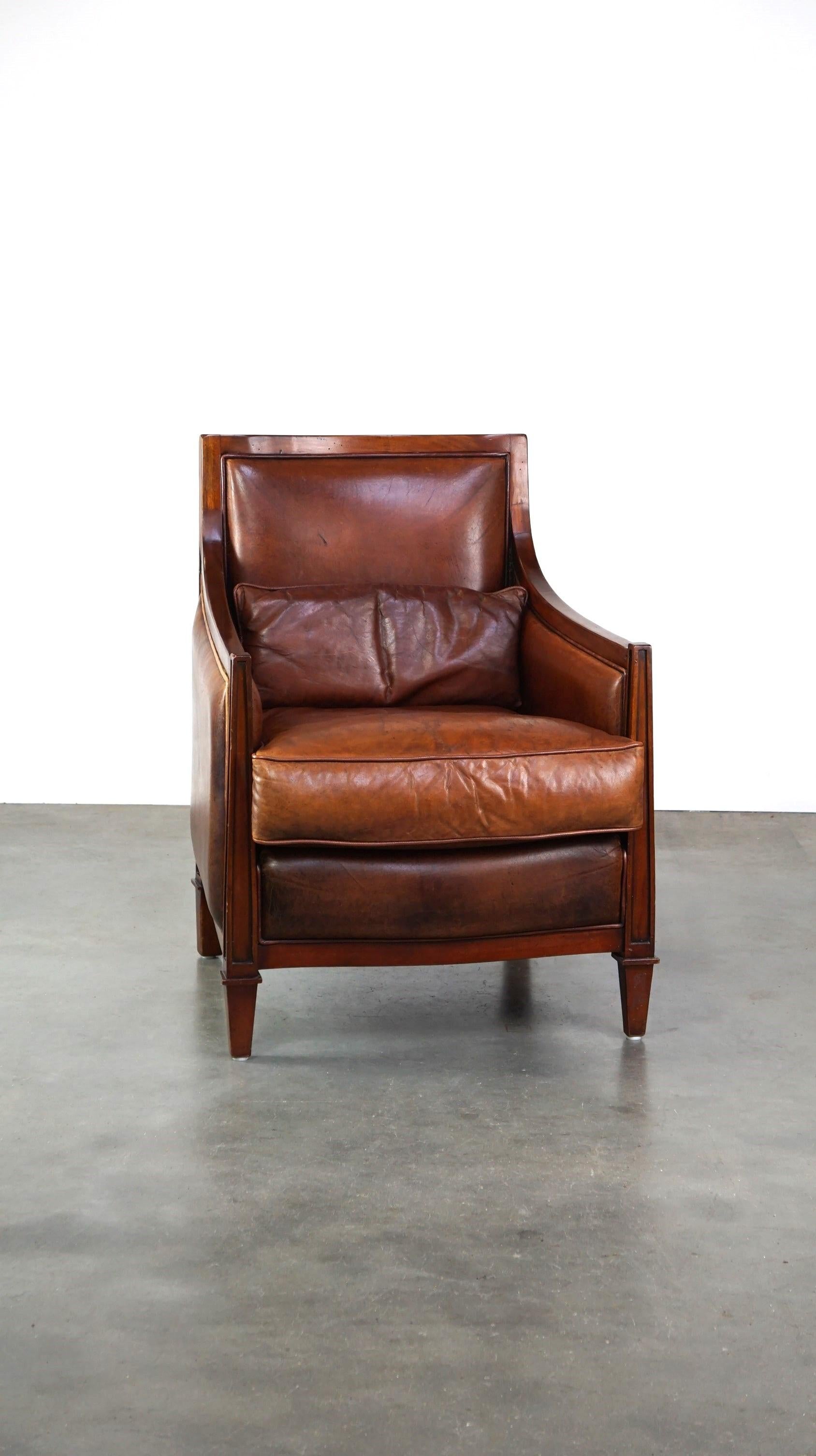 Offert ce beau et confortable fauteuil design Artdeco en peau de mouton couleur cognac combiné avec du bois.

Ce fauteuil en peau de mouton au design ArtDeco n'attire pas seulement le regard, il est aussi très confortable ! Il peut facilement