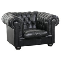 Comfortable black chesterfield armchair made of cowhide leather