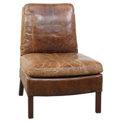 Chaise de salon confortable en cuir de vache au design unique et à la belle patine.