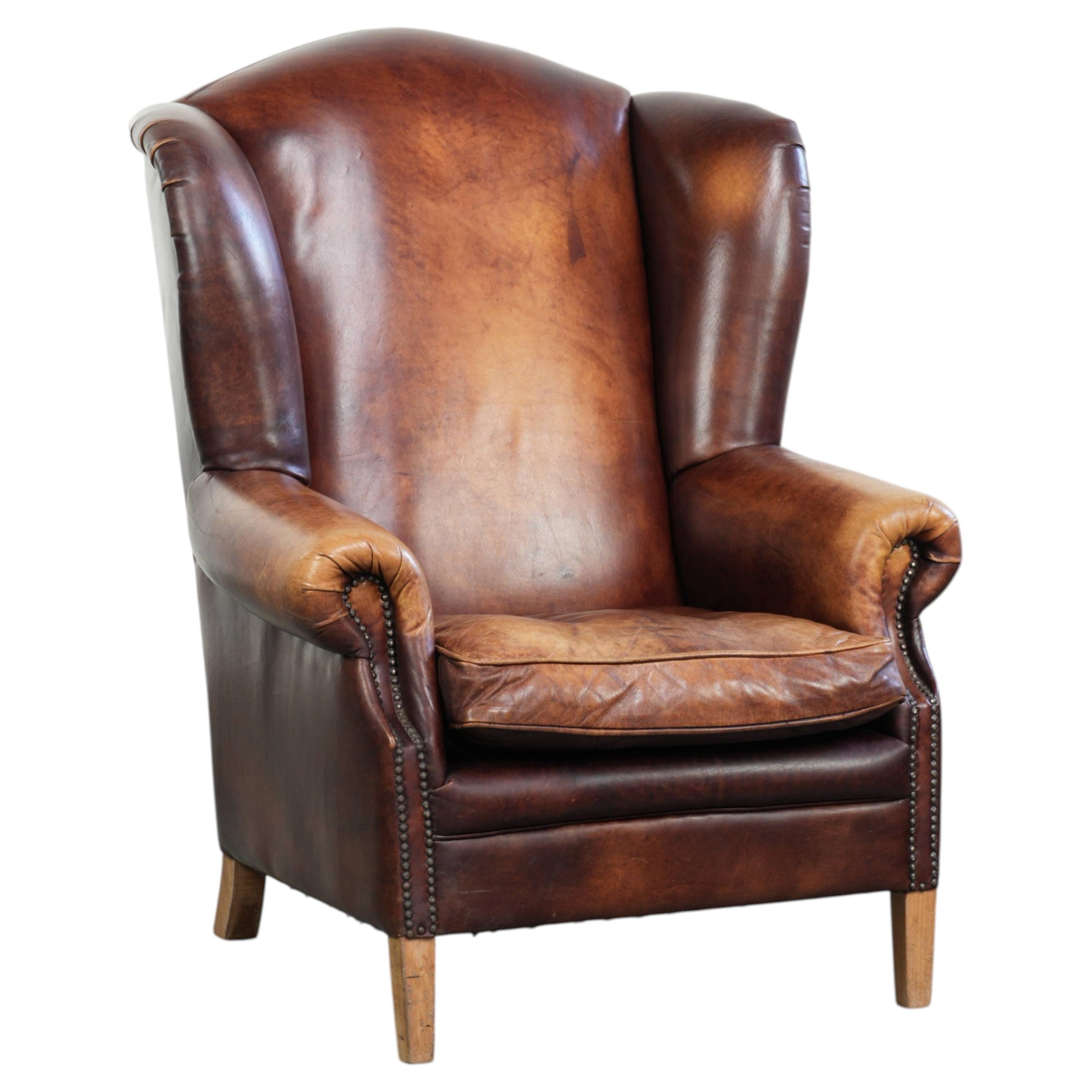 Cognac-coloured wingback armchair in English style made of cowhide ...