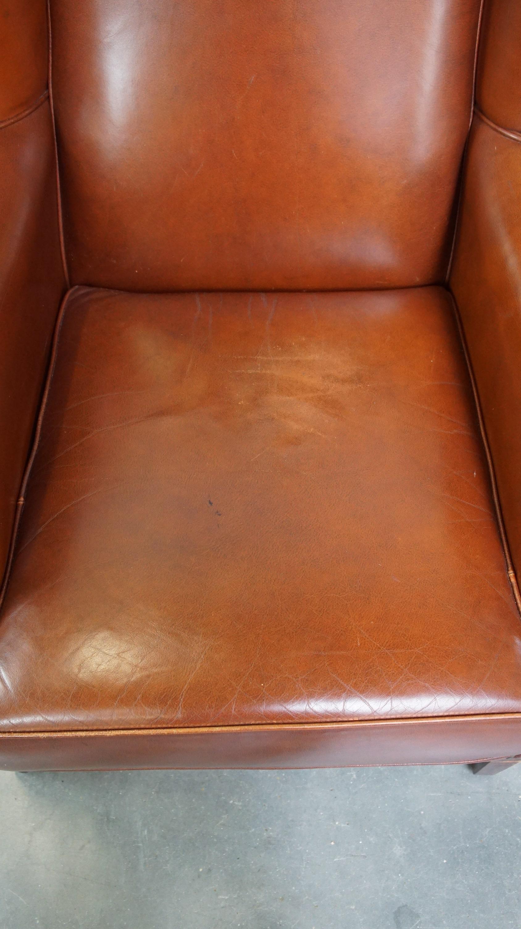 Cowhide Comfortable, luxury English-style cognac-colored leather wingback armchair For Sale