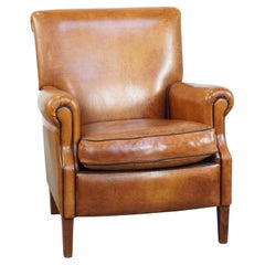 Fauteuil confortable et soigné en peau de mouton avec un liseré noir bien marqué, en bon état.