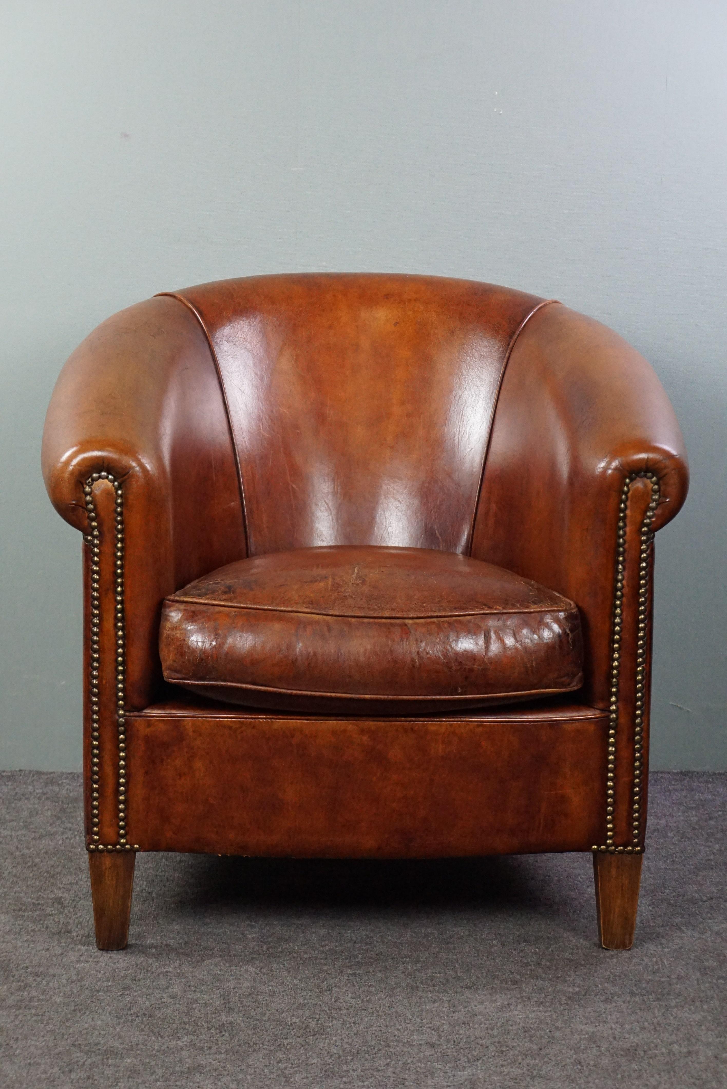 Offered is this beautiful, honest sheep leather club armchair in a fantastic warm cognac/chestnut shade. This beautiful, timeless piece elicits immediate desire in many people, and we completely understand why! There are probably very few who
