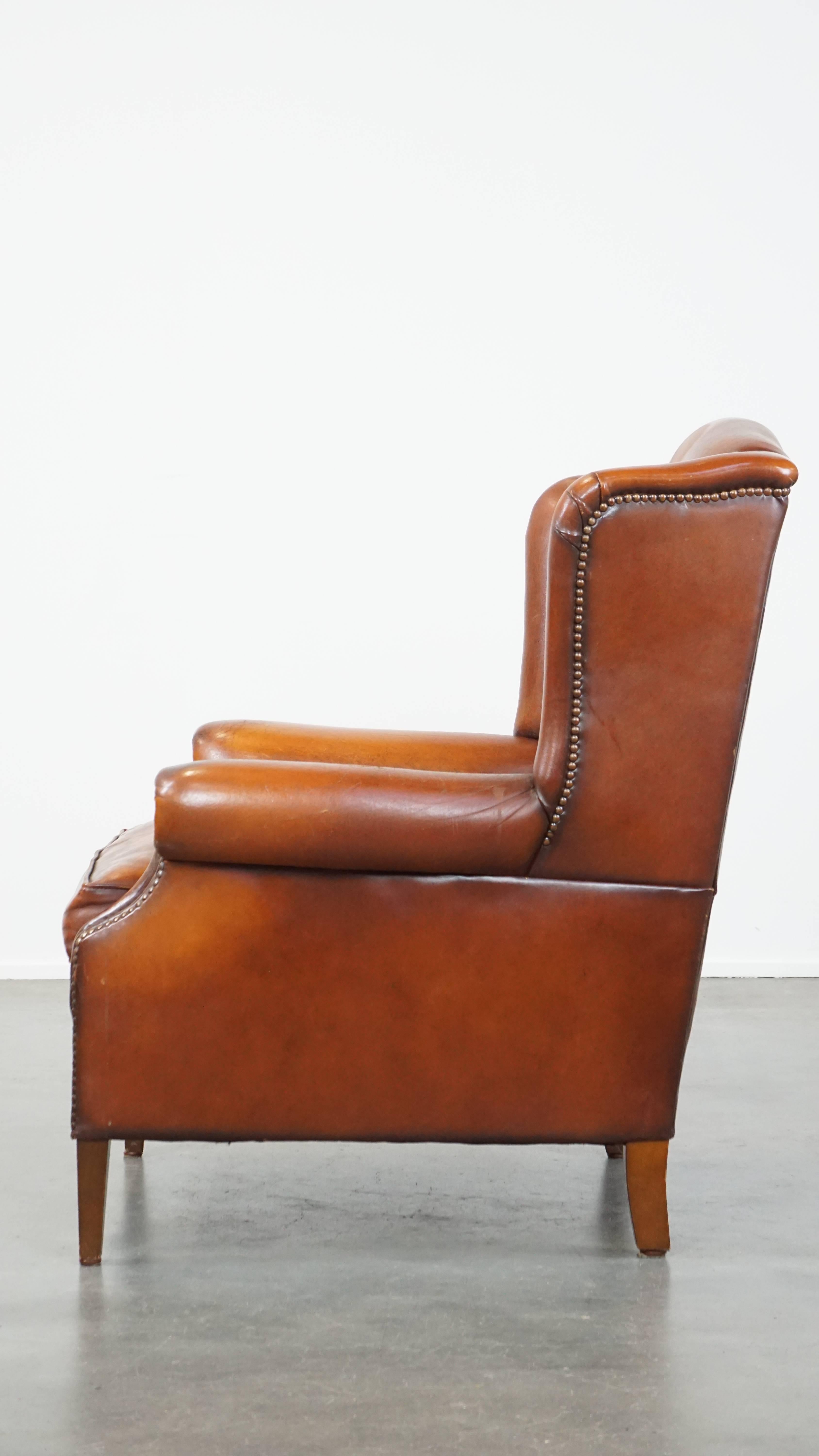 20th Century Comfortable sheepskin leather wingback chair with a warm color scheme and patina For Sale