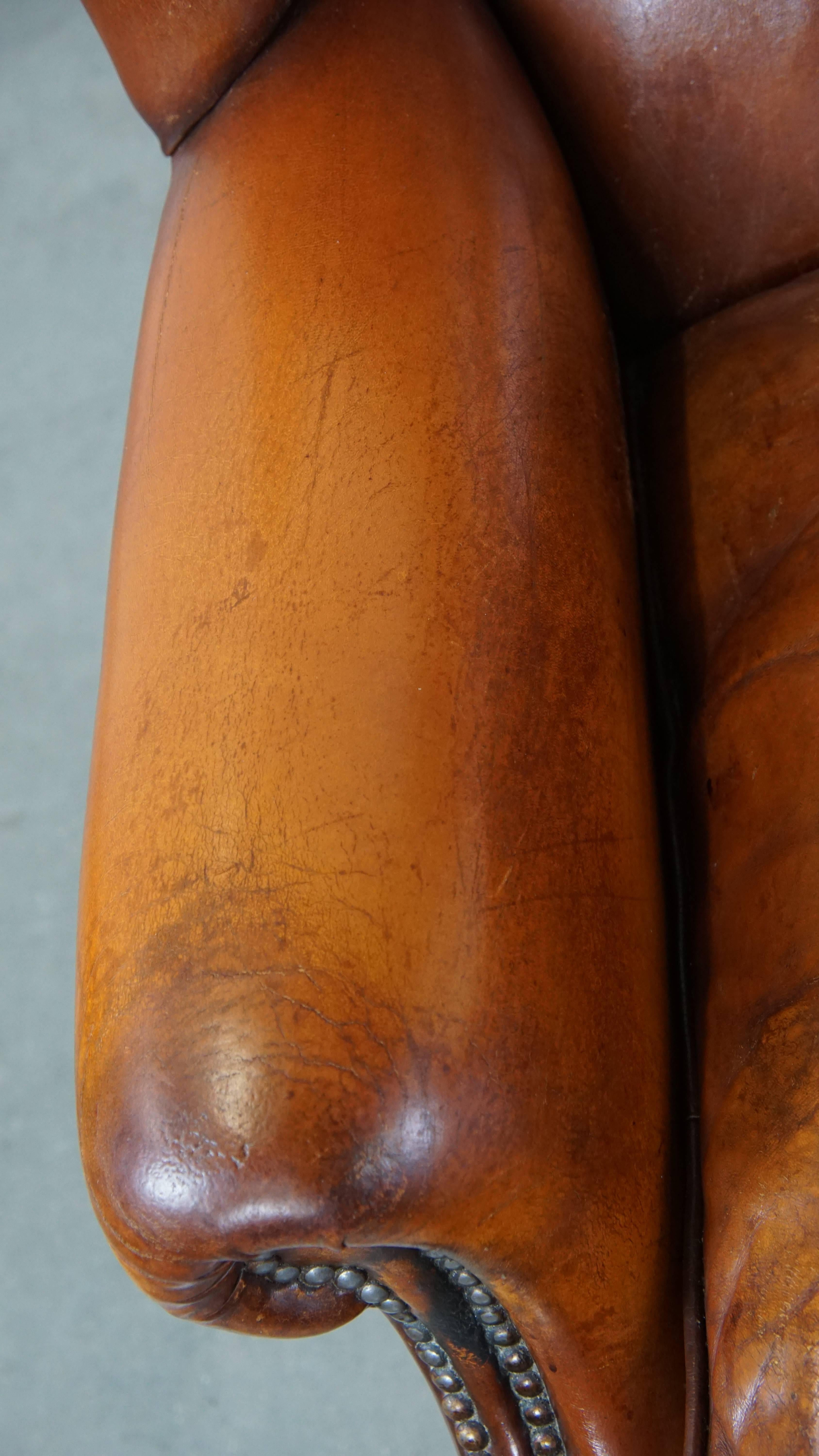 Comfortable sheepskin leather wingback chair with a warm color scheme and patina For Sale 1