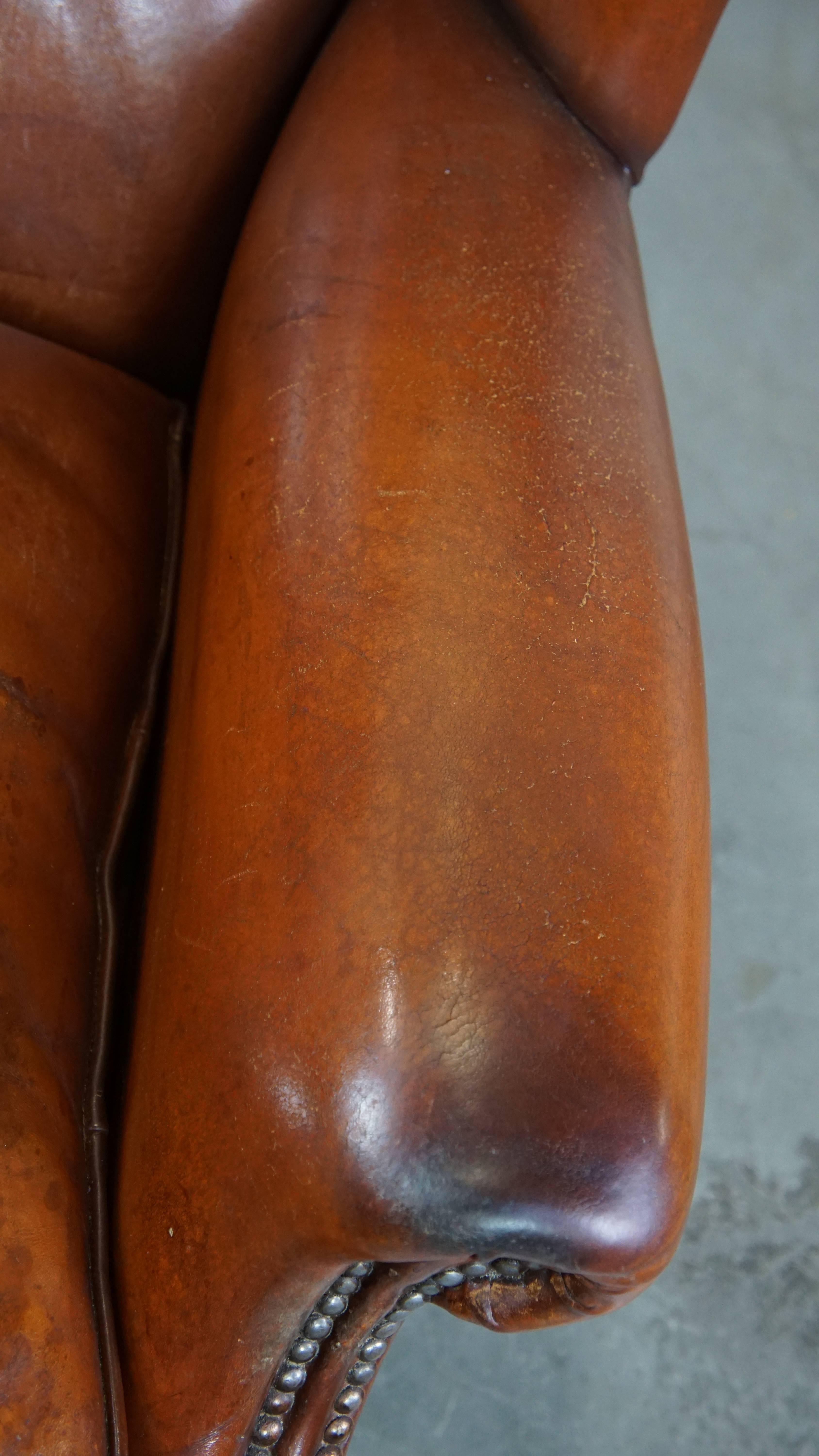 Comfortable sheepskin leather wingback chair with a warm color scheme and patina For Sale 2