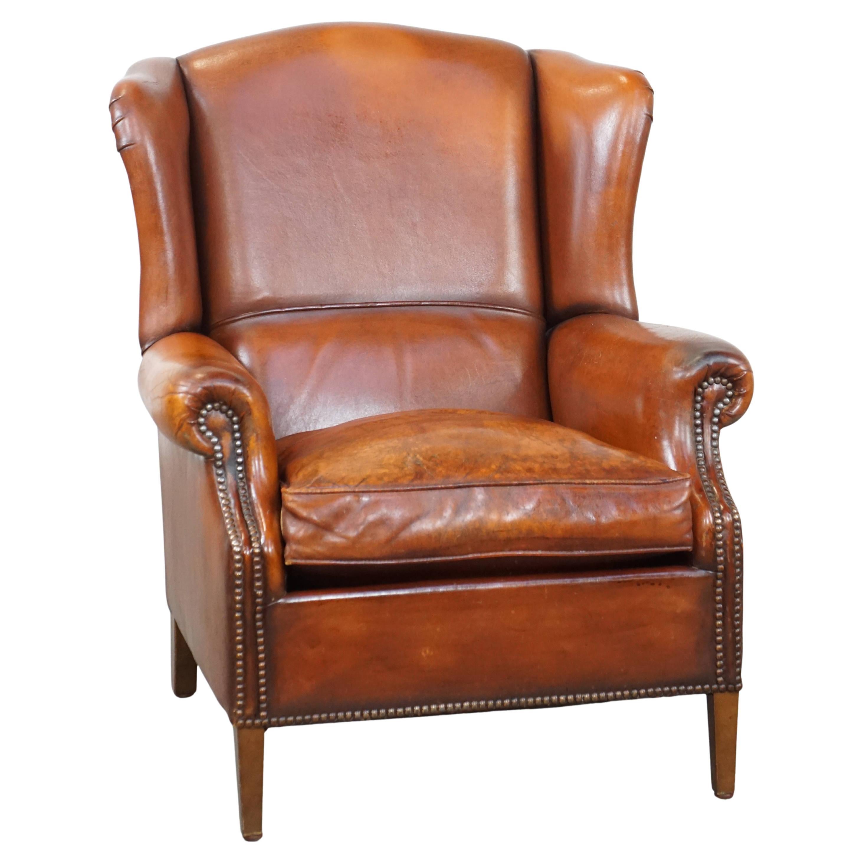 Comfortable sheepskin leather wingback chair with a warm color scheme and patina