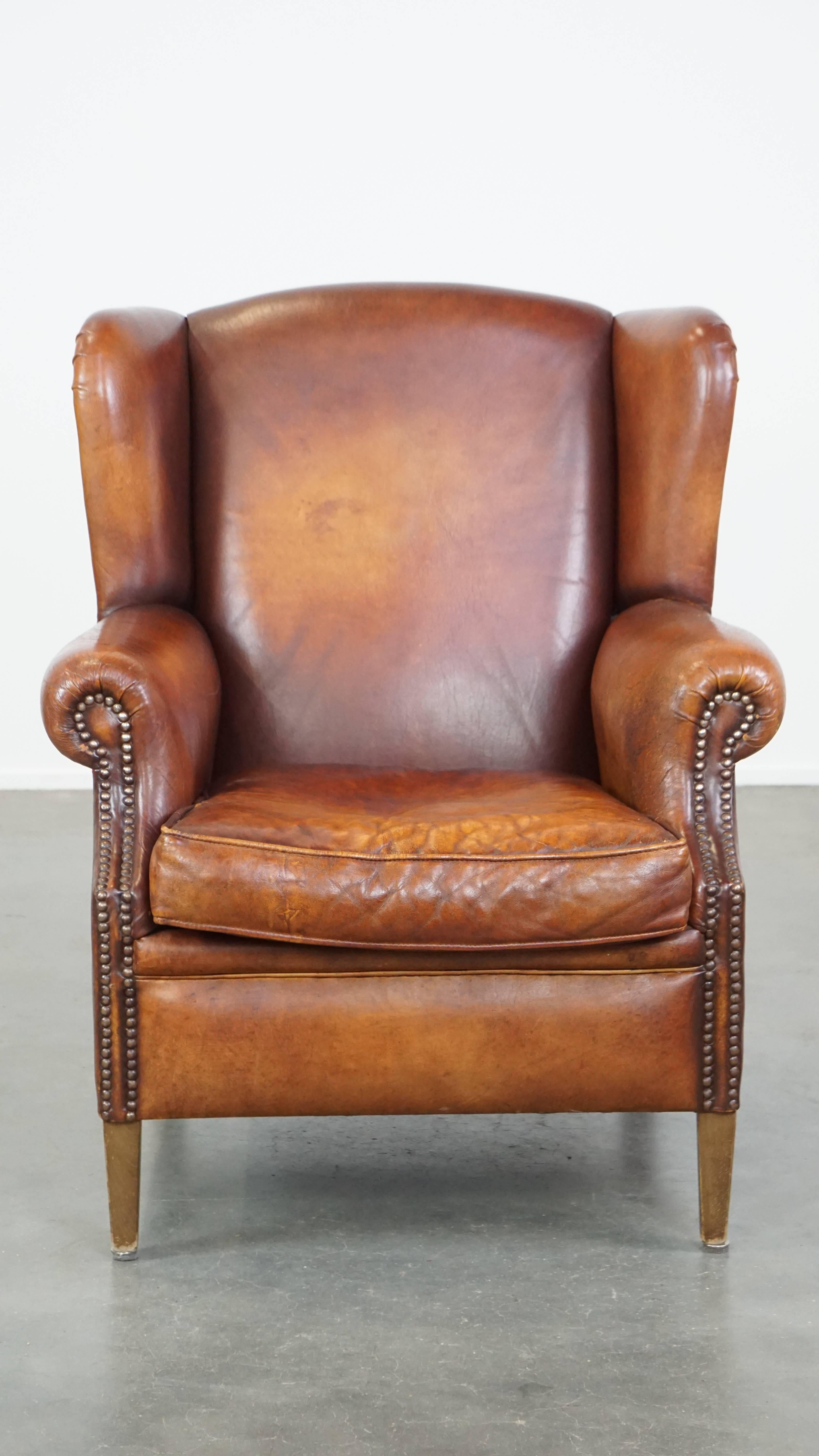 Who could possibly resist such a beautifully warm-colored sheepskin leather wingback armchair? We certainly can't! This fantastic vintage wingback chair boasts timeless English charm and comfort, with elegant detailing finished with decorative