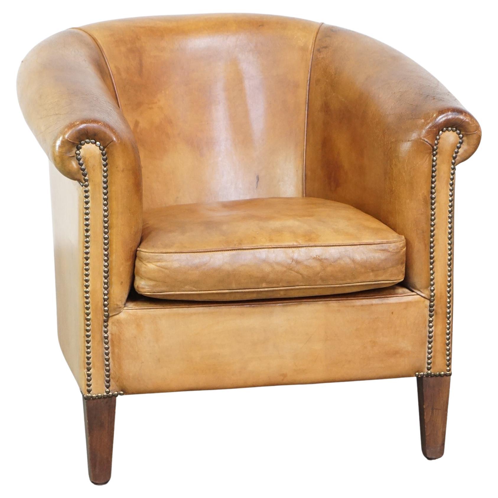 Cómodo sillón club de piel de oveja de colores cálidos acabado con clavos decorativos