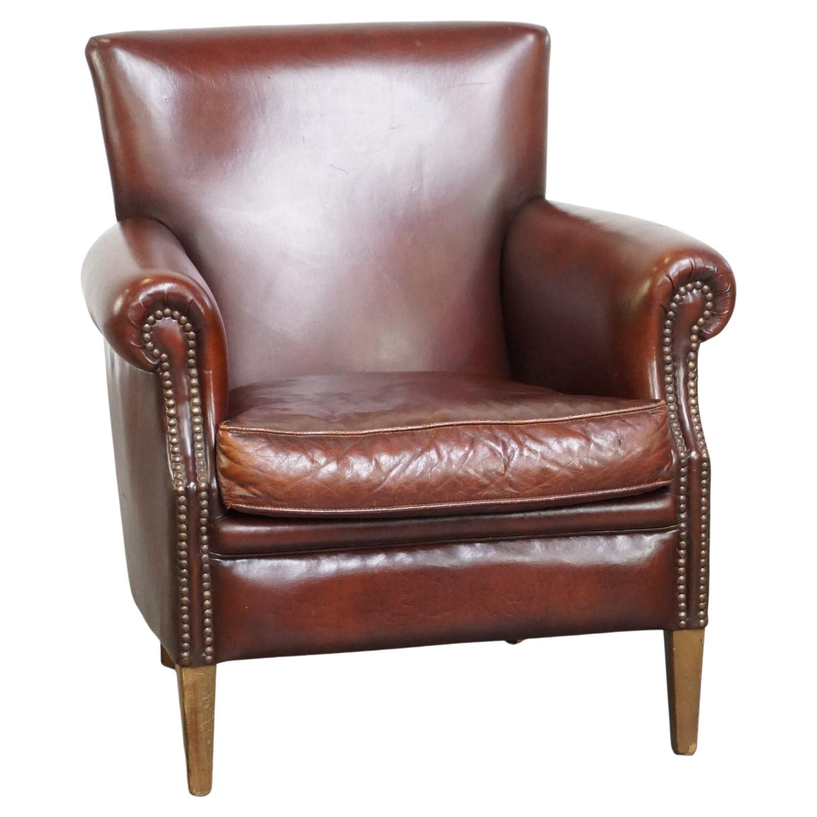 Fauteuil confortable et bien fini en cuir de mouton de couleur foncée