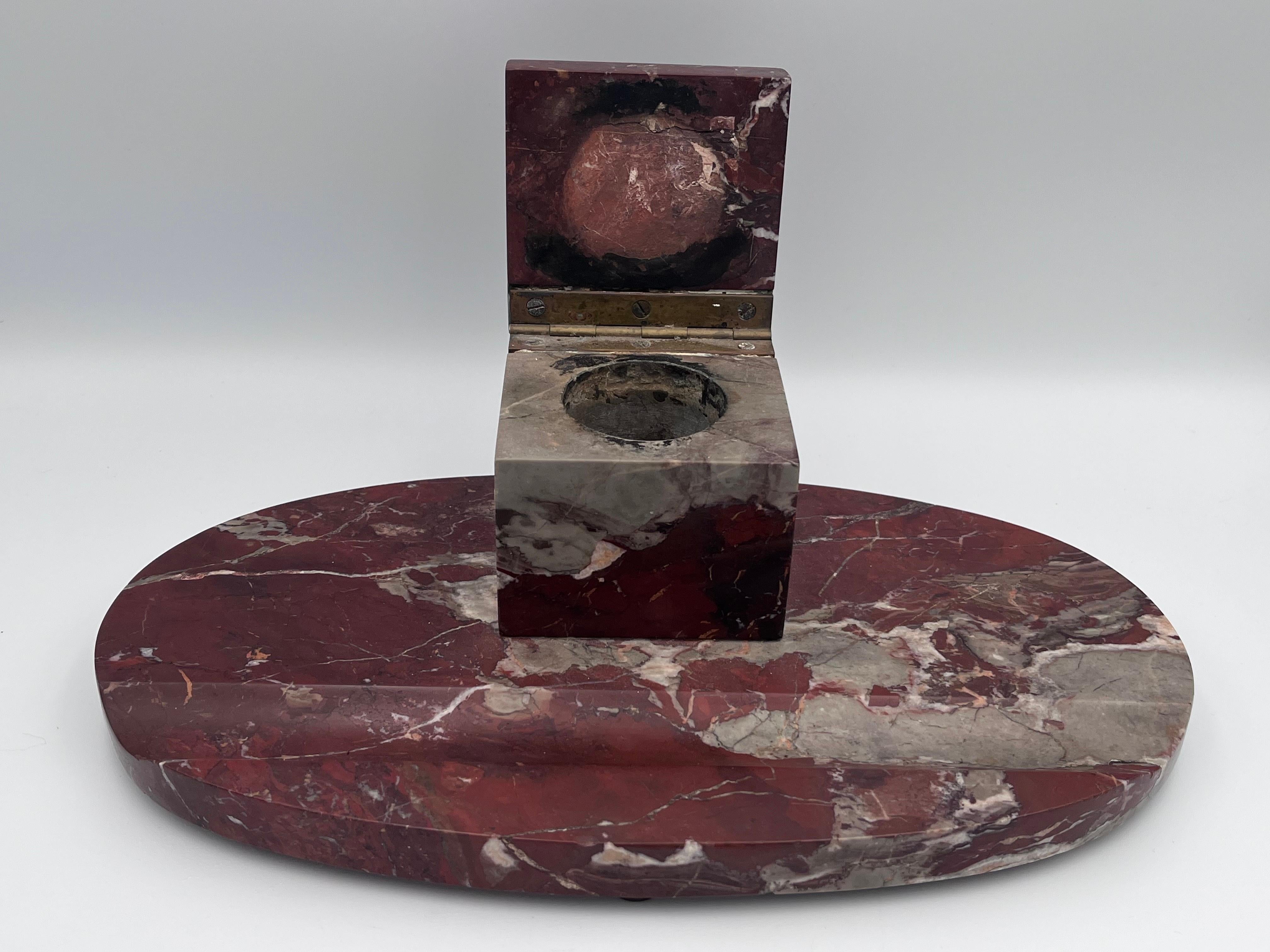 Imponente calamaio e poggiapenna in marmo rosso Levanto Art Deco degli anni '20

Questo calamaio e poggiapenne in stile Art Déco, risalente agli anni '20, è realizzato in marmo rosso Levanto riccamente scolpito,  un materiale apprezzato per la sua