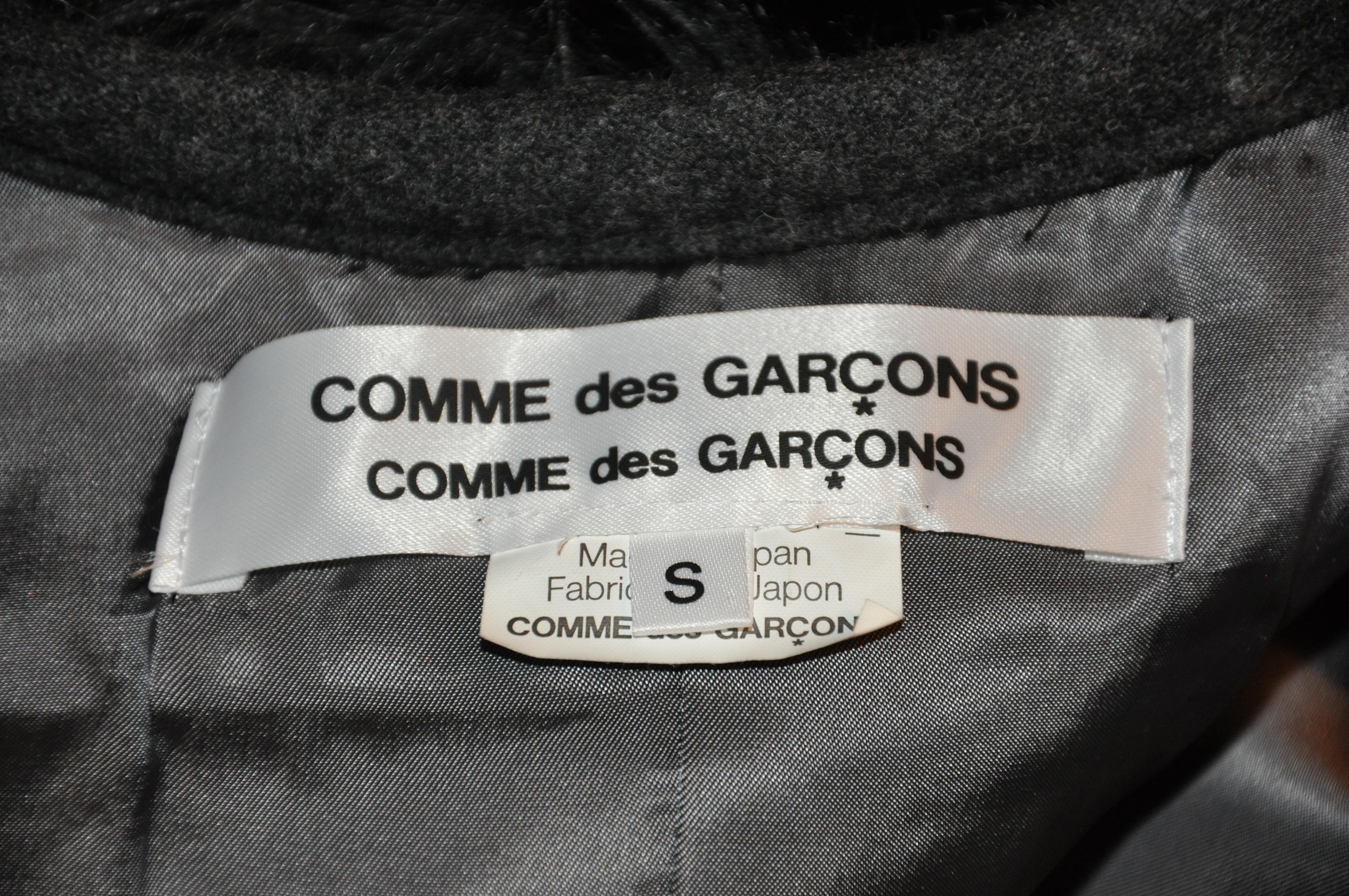 Le gilet ouvert en fausse fourrure noire entièrement doublé Comme des Garcon Double Label est agrémenté d'un passepoil détaillé en laine anthracite ainsi que de boutons gris. La doublure intérieure comporte deux poches plaquées près de l'ourlet