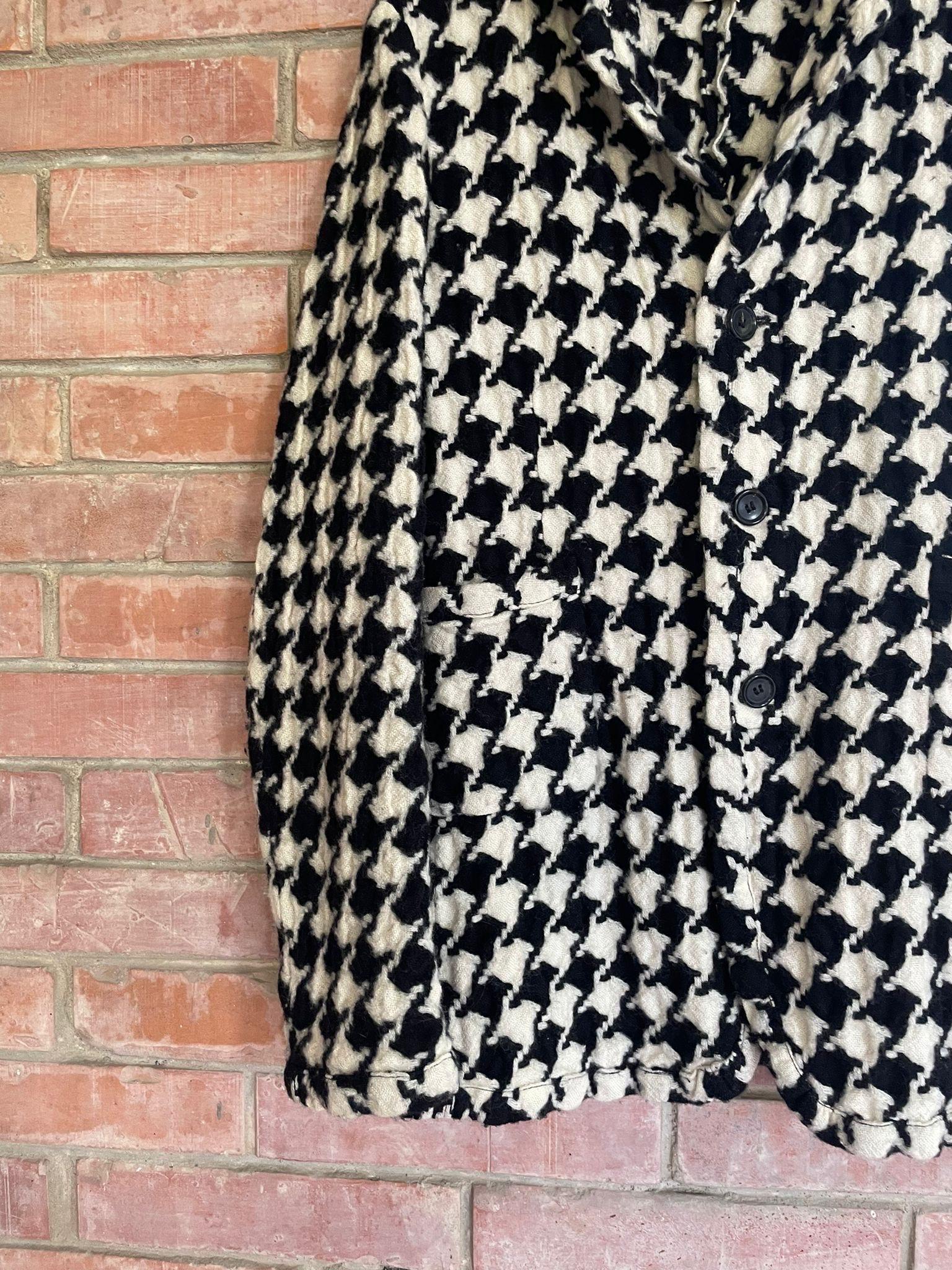 Giacca Comme Des Garçons con motivo pied de poule bianco e nero in 100% lana, taglia S. Due tasche sul davanti e chiusura con bottoni. 
Spalle 42 cm 
Manica 60 cm
Seno 44 cm
68 cm di lunghezza 
Presenta alcuni segni di utilizzo.