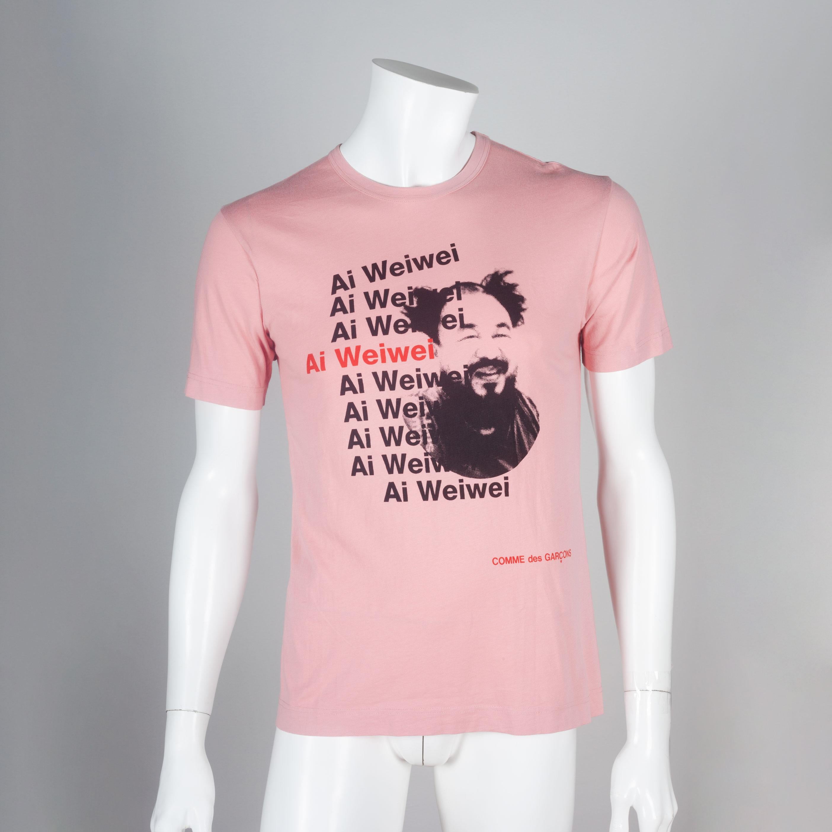 Comme des Garçons pink Ai Weiwei tee from 2010. The t-shirt features the Chinese contemporary artist and activist's portrait with his name repeating down the center front. 

YEAR: 2010
MARKED SIZE: M
US WOMEN'S: L
US MEN'S: M
FIT: Regular
CHEST: