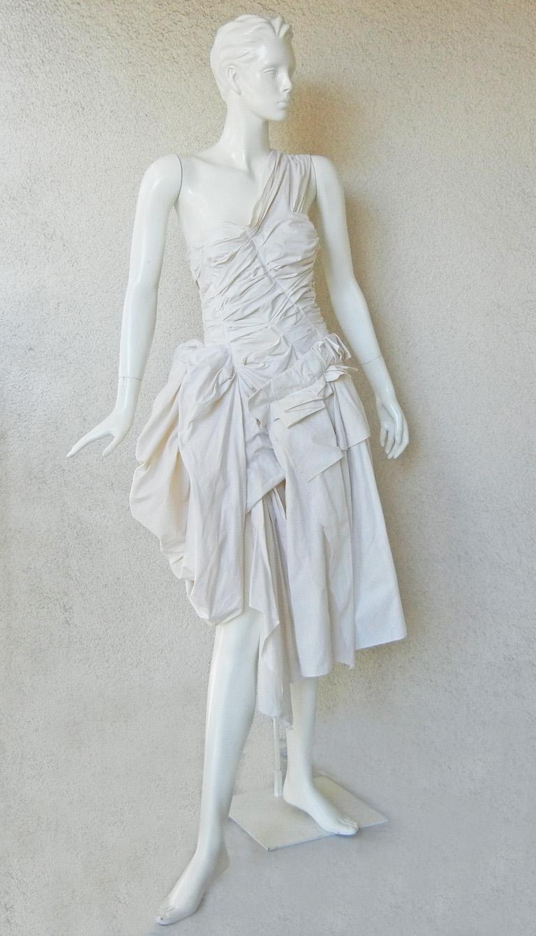 Rei Kawakubo for Comme des Garcons high concept creation with  Victorian flair.  Most likely inspired by Vivienne Westwood's wench style dresses.   Asymmetric heavy cotton dress  extraordinarily constructed with  fan pleating and  manipulation of