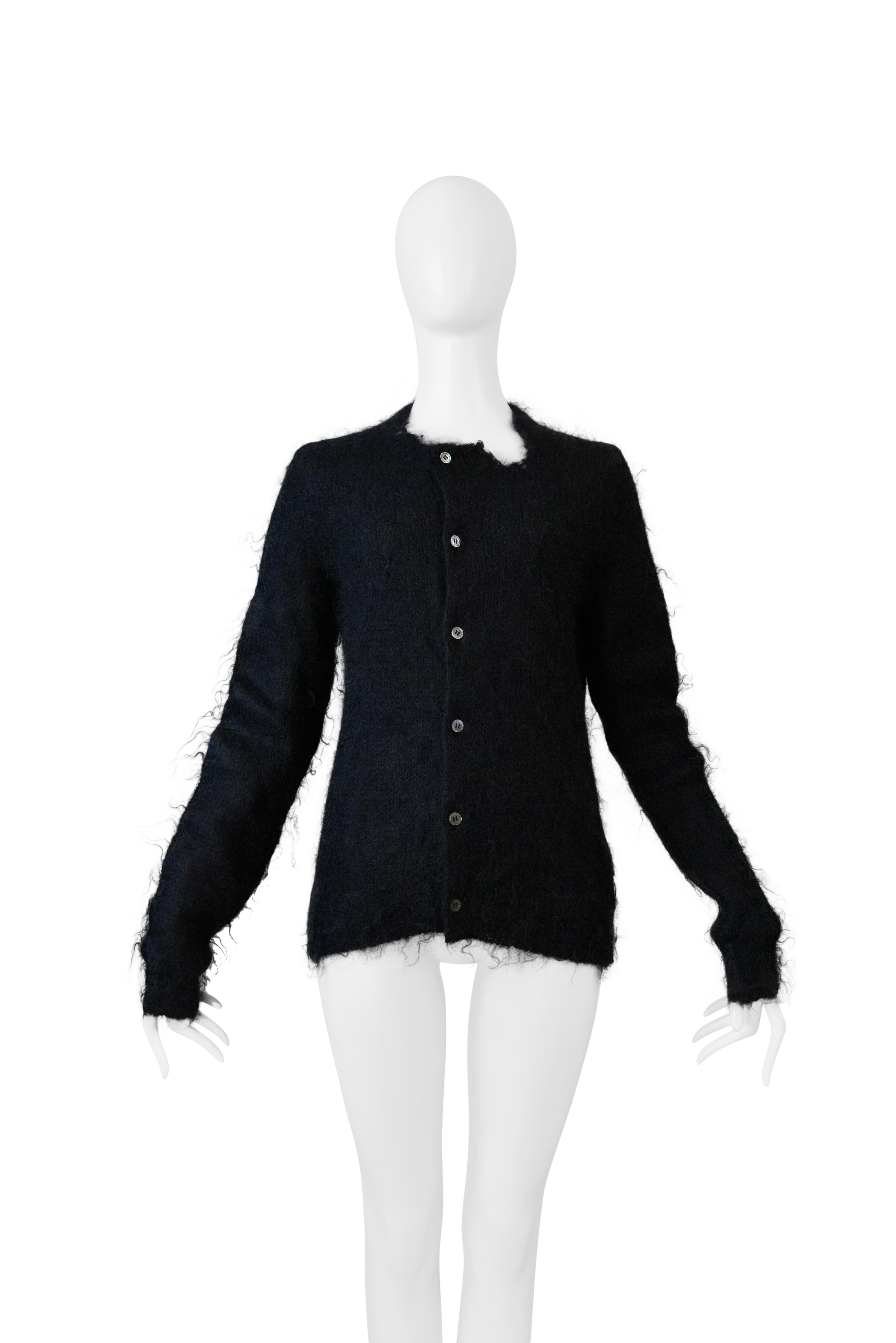 Resurrection Vintage a le plaisir de vous présenter un pull cardigan vintage Comme Des Garçons en mohair noir délavé de la collection 2001-02, avec fermeture par bouton sur le devant, découpe à l'encolure, manches longues, mohair brossé, et longueur