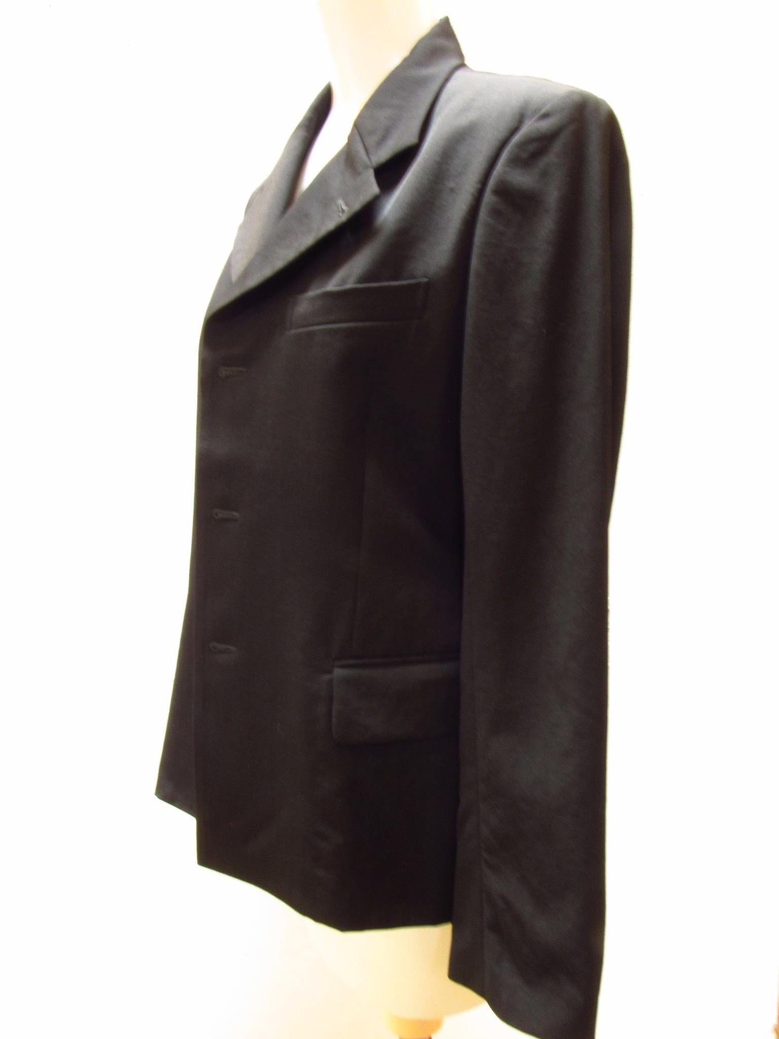 Ce blazer noir classique de Comme Des Garçons comporte trois boutons le long de la patte de boutonnage et un bouton caché au niveau du col. Deux poches de hanches sur le devant et une seule poche de poitrine, ainsi que des boutons doubles aux