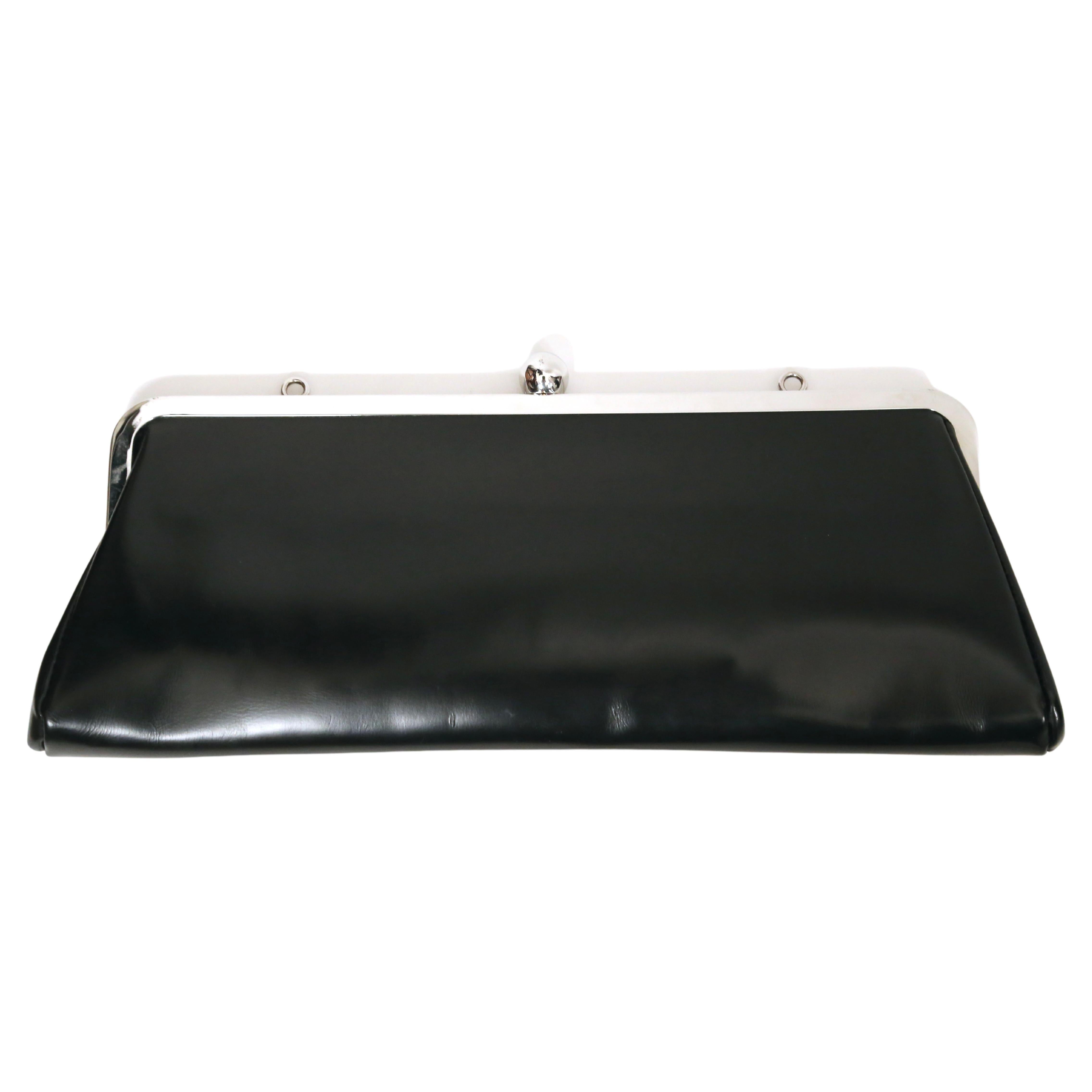Black highly polished leather bag with adjustable brown nylon shoulder strap and silver kiss lock frame designed by Katsuyuki Yoshida for Comme Des Garcons. Approximate measurements: width 13.33
