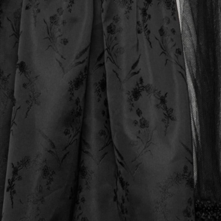 Esta falda de Comme des Garcons, confeccionada a medida en una silueta chic, aportará a tu aspecto una feminidad y un aplomo inagotables. Está cosida con malla negra y tela de seda con bordados florales, decorada con formaciones de volantes. ¡Añade