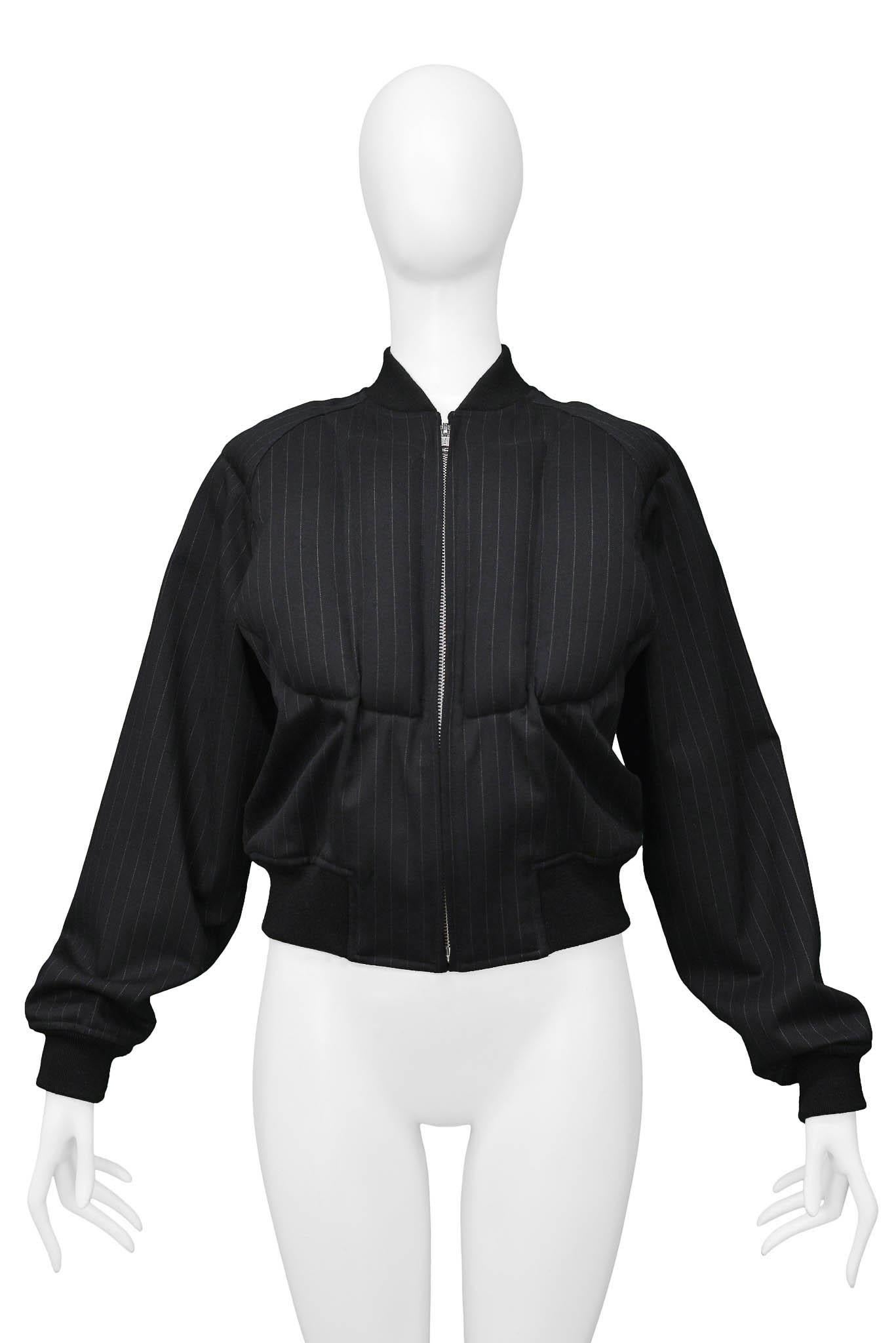 Resurrection Vintage a le plaisir de vous proposer une veste vintage à rayures noires de la marque Comme des Garcons, avec un padding sur le devant et le dos de la veste, une fermeture éclair en métal, et des bordures noires le long des manches, de