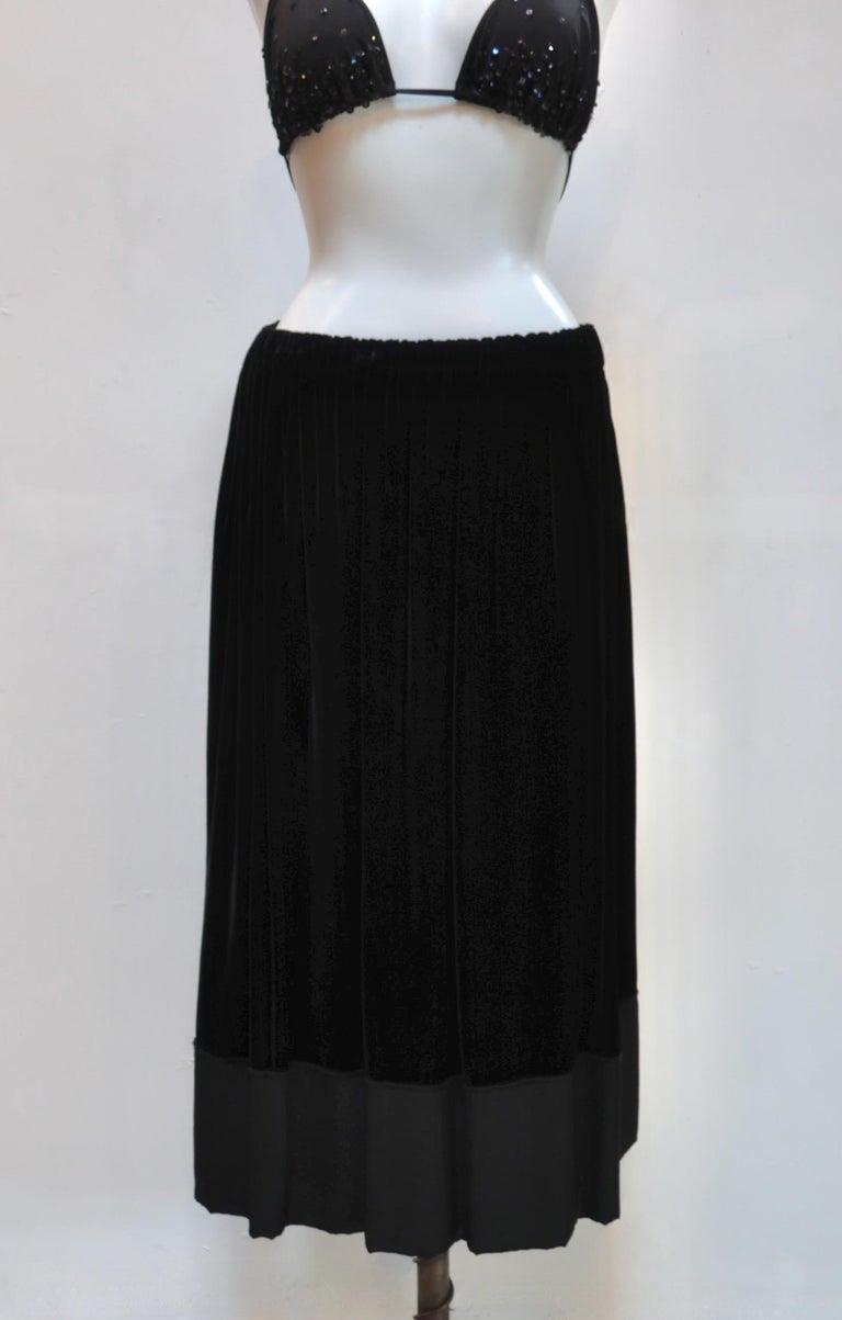 This easy pull on black velvet skirt has an elasticized drawstring waist, side seam pockets, and a contrasting fabric hemline with raw, exposed seams. 