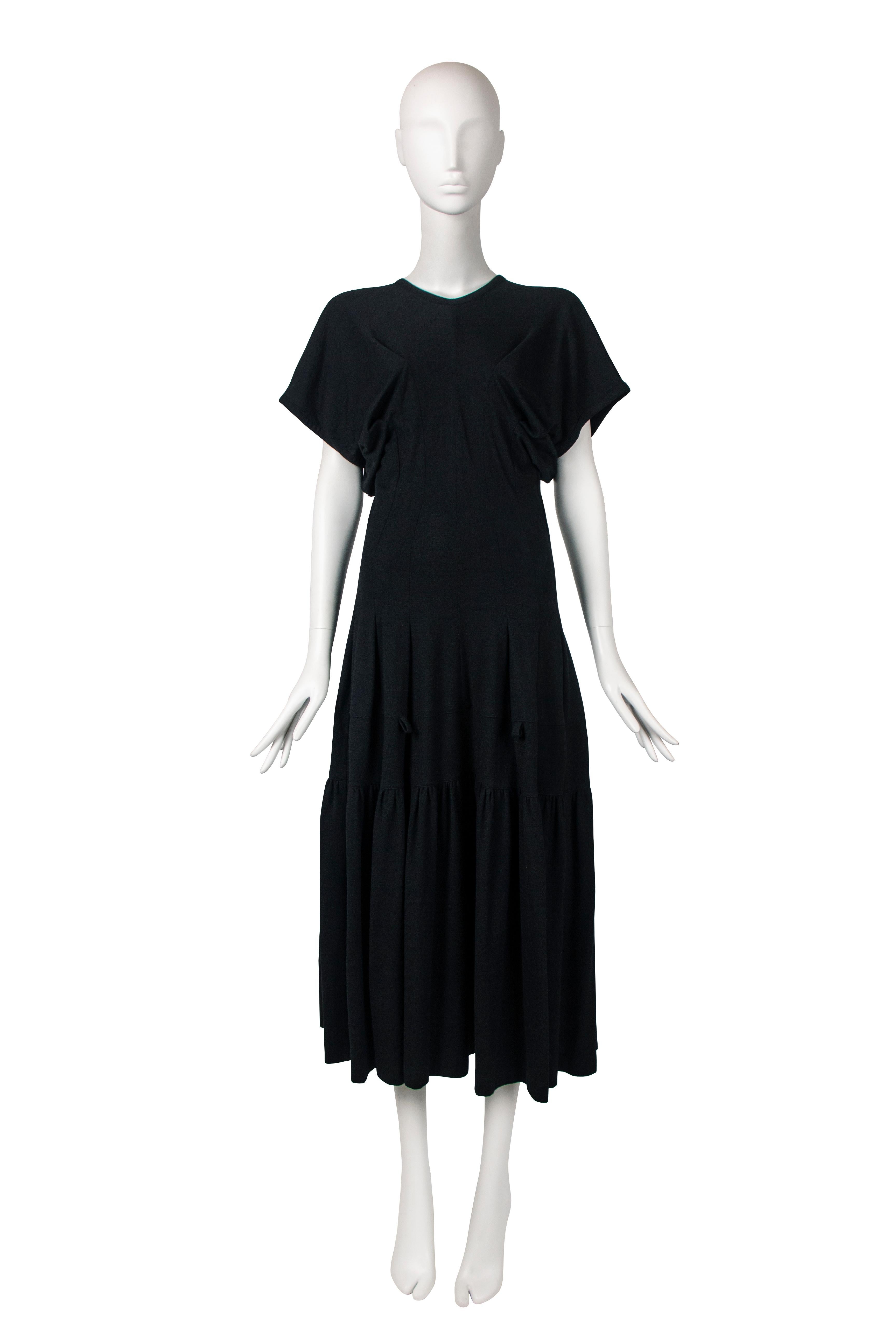 This Comme Des Garcons dress from the fall-winter 1989 collection is a panelled long wool dress with interesting design features. The dress has 5 seams running down from the bust that shape the garment and create a form-fitting midsection. The skirt