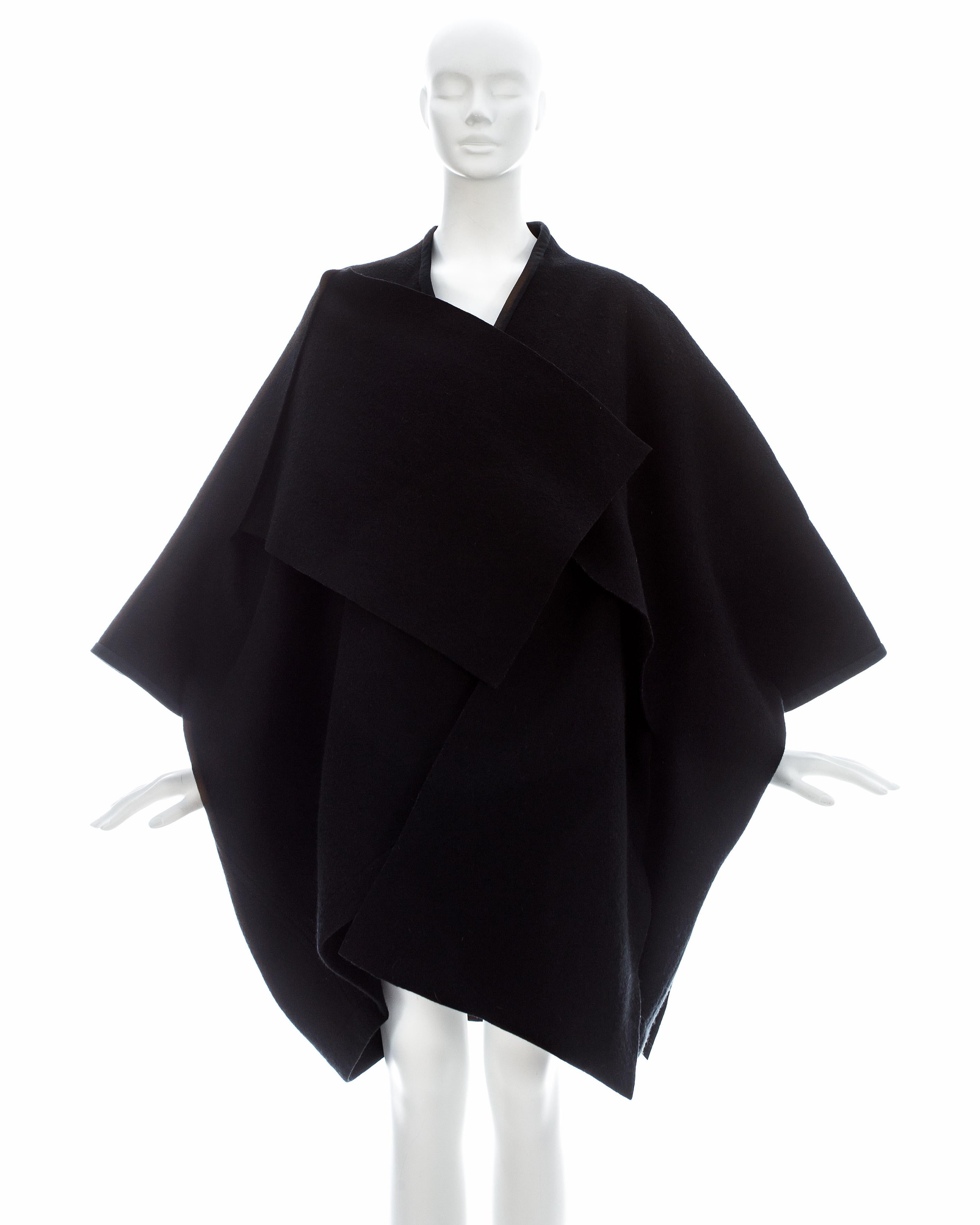 Comme des Garcons; Black wool felt coat made from two rectangular panels woven together through large slits cut into the fabric. There are no buttons or fasteners.  

Fall-Winter 1983