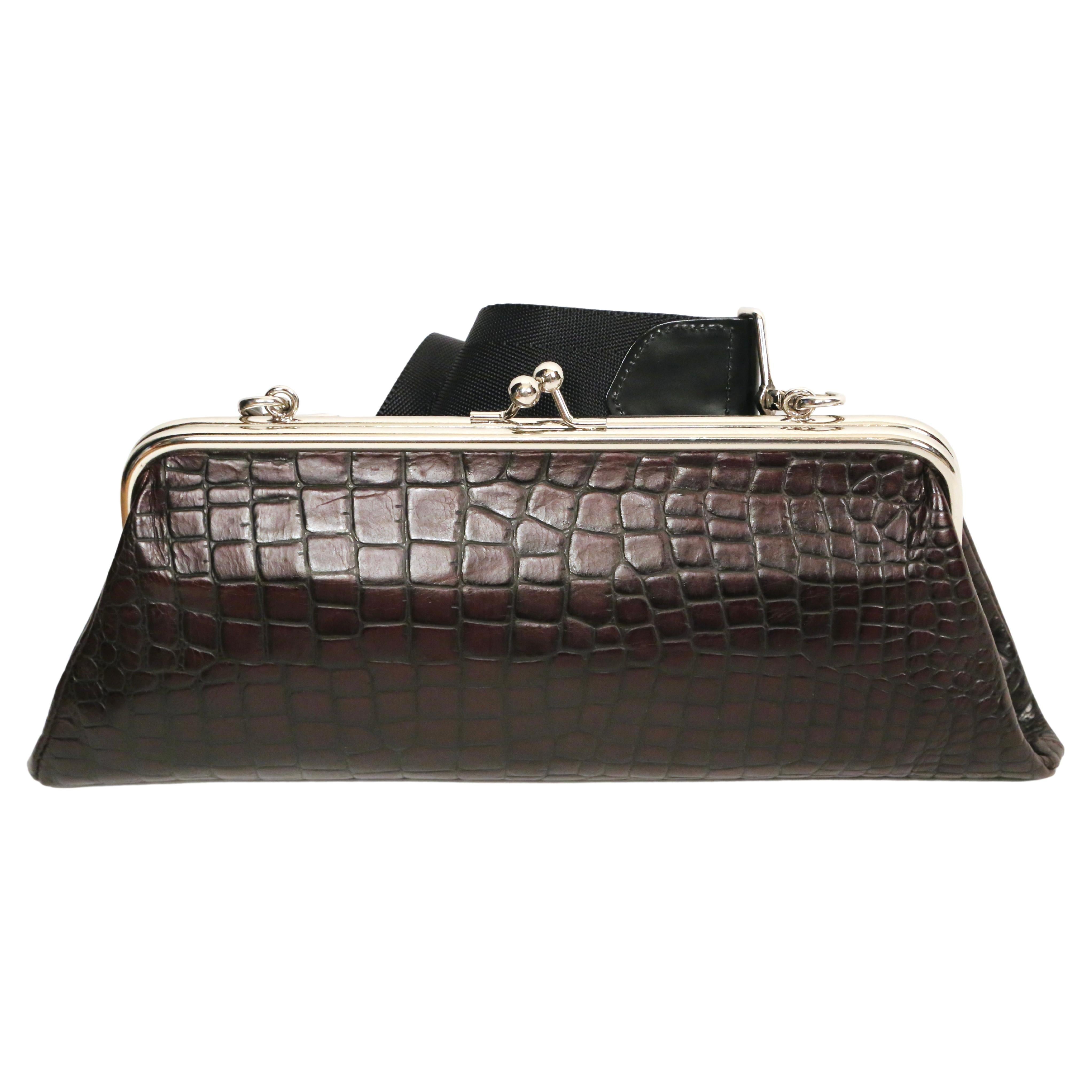 Brown, crocodile embossed, leather bag with adjustable black nylon shoulder strap and silver kiss lock frame designed by Katsuyuki Yoshida for Comme Des Garcons. Approximate measurements: width 13