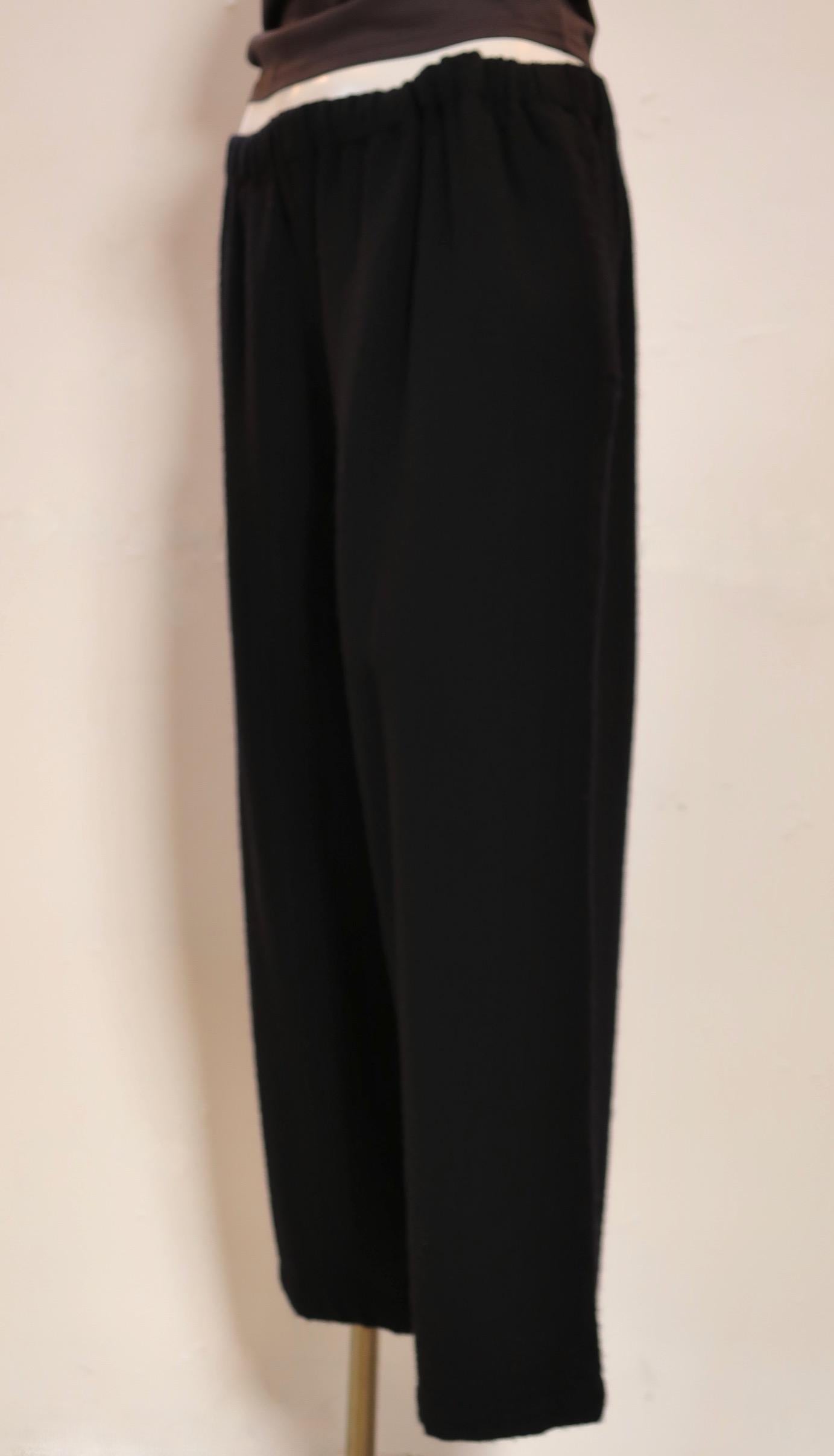 These generous black wool pants from Comme des Garçons are cropped in length, have an elasticized waist, an inner drawstring, and two side seam pockets. 