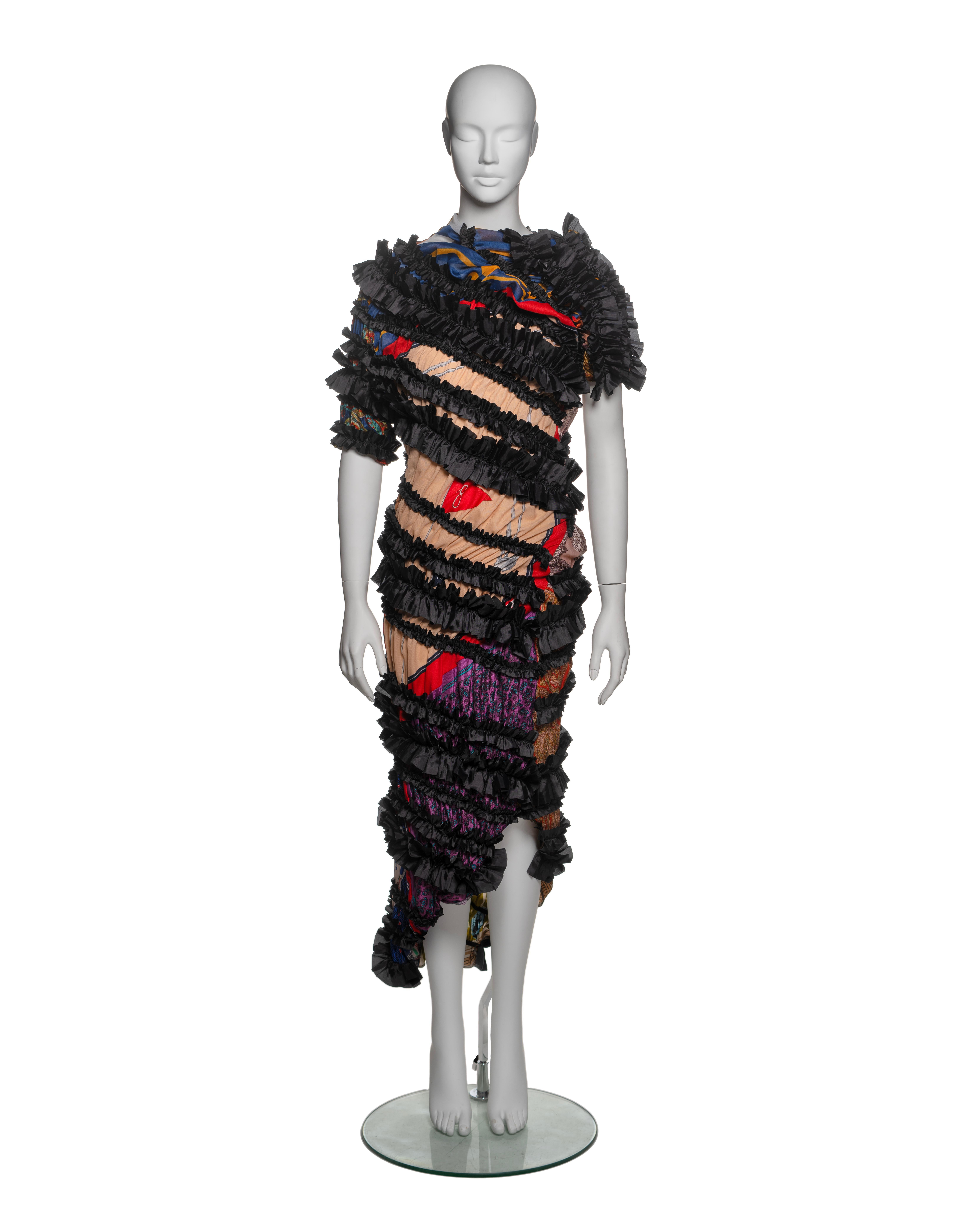 Comme des Garçons, Otoño-Invierno 2011: Un vestido confeccionado con pañuelos vintage en una variedad de estampados y colores vibrantes, como rojo, azul, dorado y morado, yuxtapuestos con cintas de satén negras con volantes. El diseño drapeado