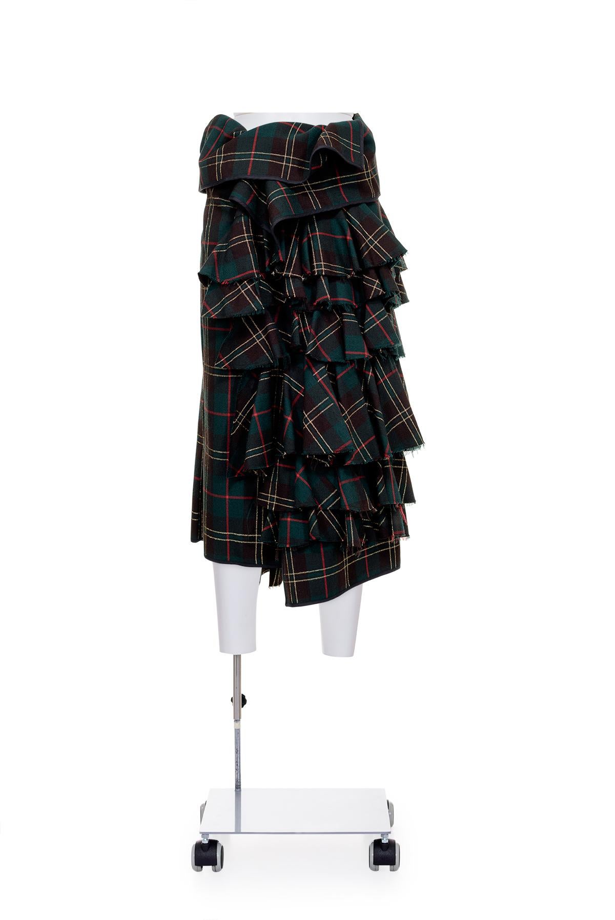 Fall Winter 1999 tartan sarong skirt with lurex details and ruffles by Comme des Garçons.
Pin closure.
The composition tag is missing, seems to be made of wool.